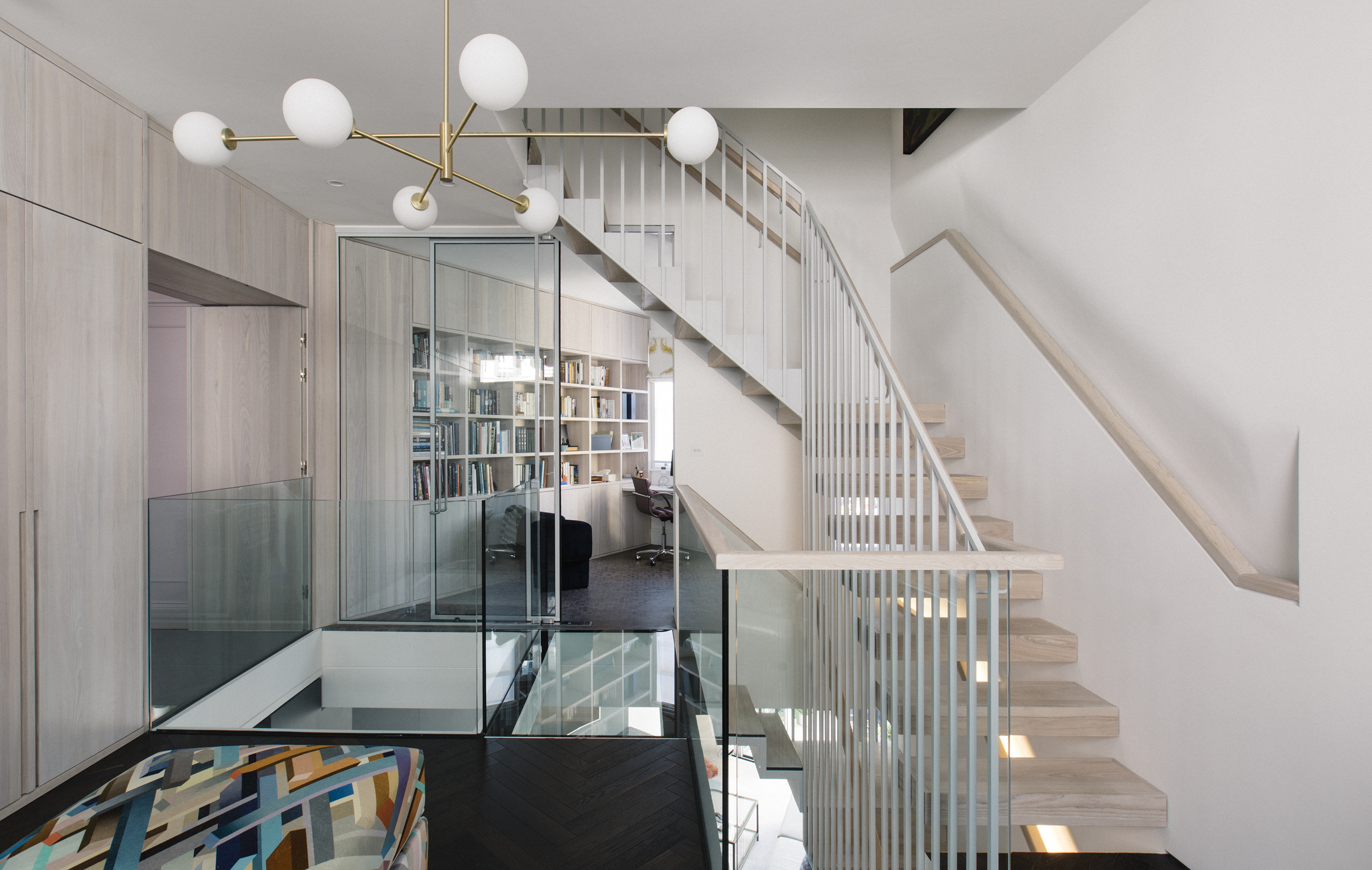A modern chandelier and glass bridge greet visitors in the entrance hall