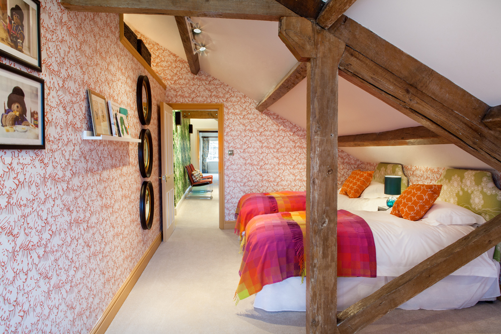 A guest bedroom in the attic area created with children in mind, mixing original beams with a fun, colourful and practical scheme