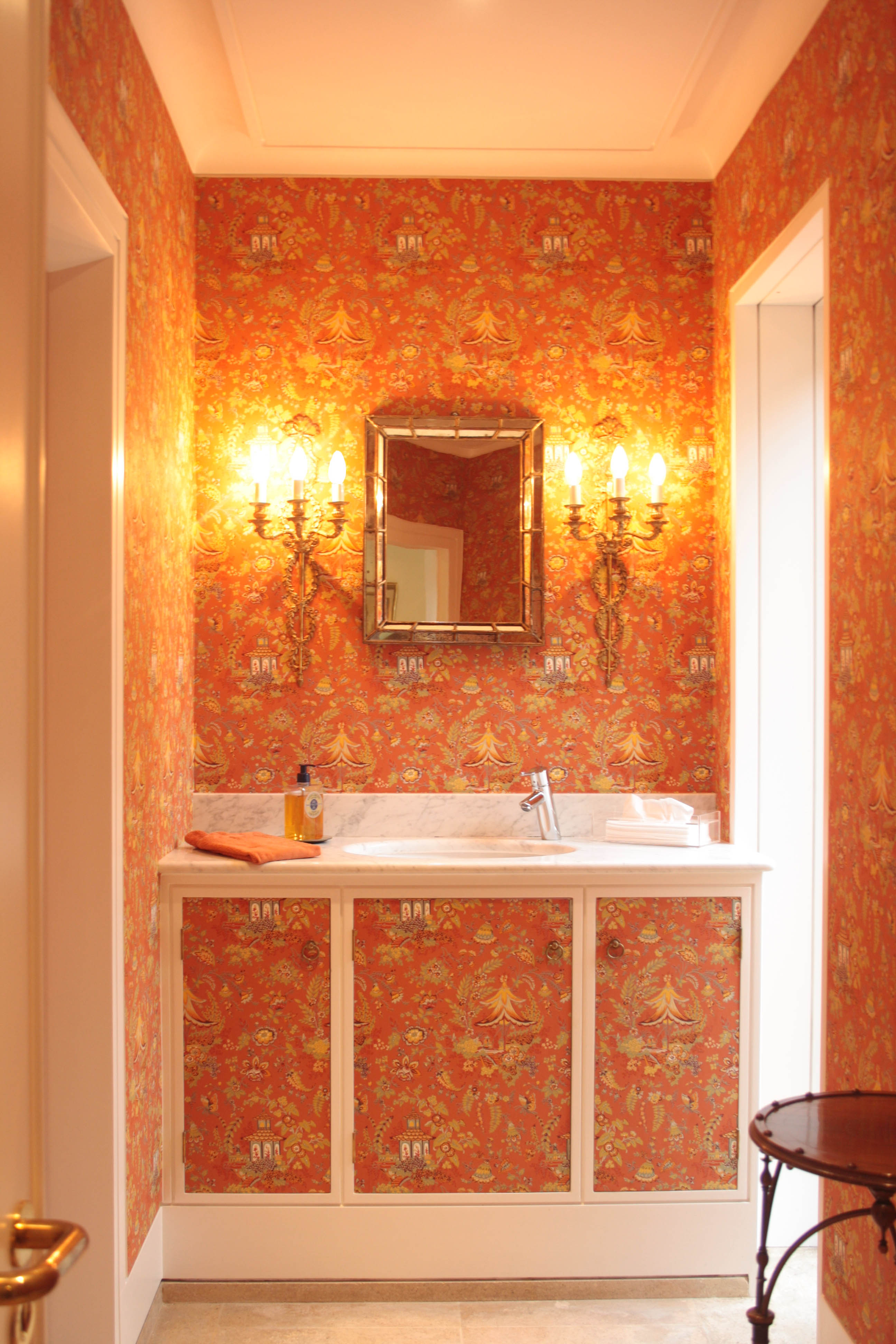 The Cloakroom's burnt orange Chinoiserie wallpaper is freshened by the white bathroom marble
