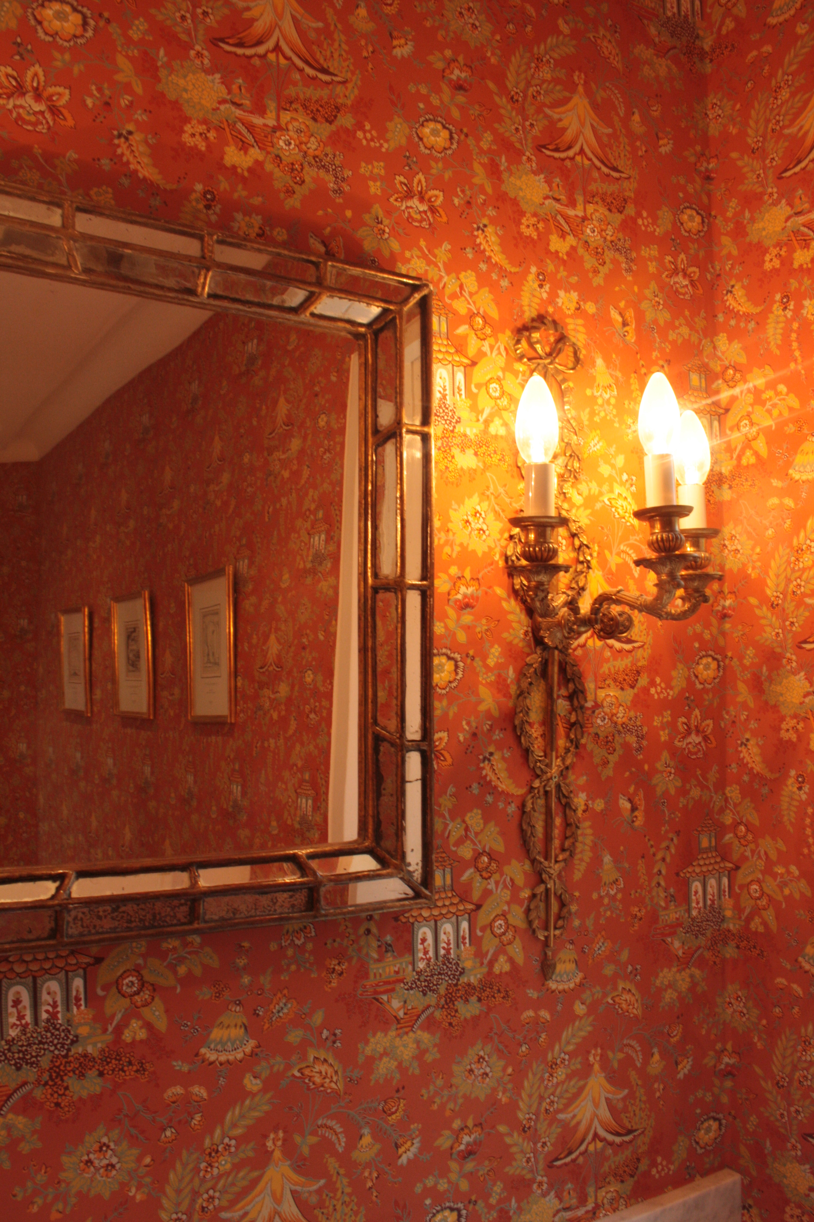 The Cloakroom Chinoiserie wallpaper, antique gilt mirror and wall sconces in detail