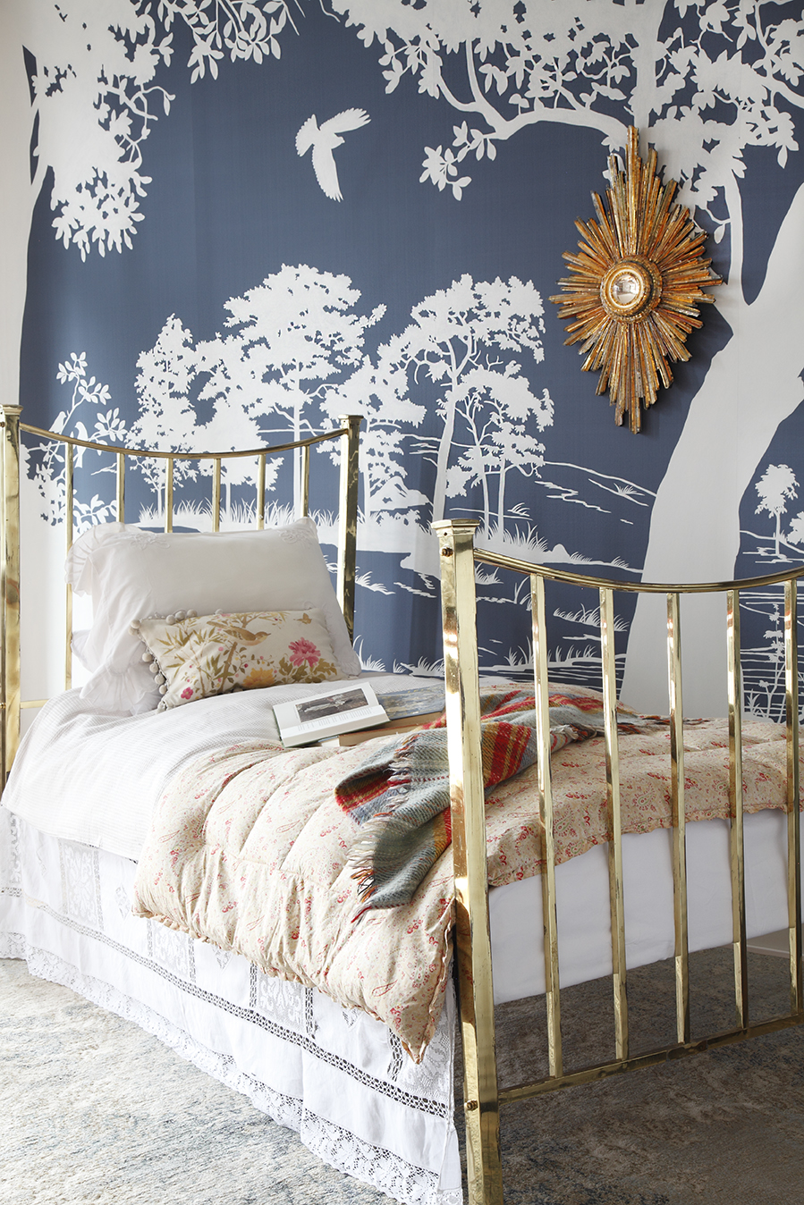 Romantic brass bed against a blue and white pictorial wallpaper