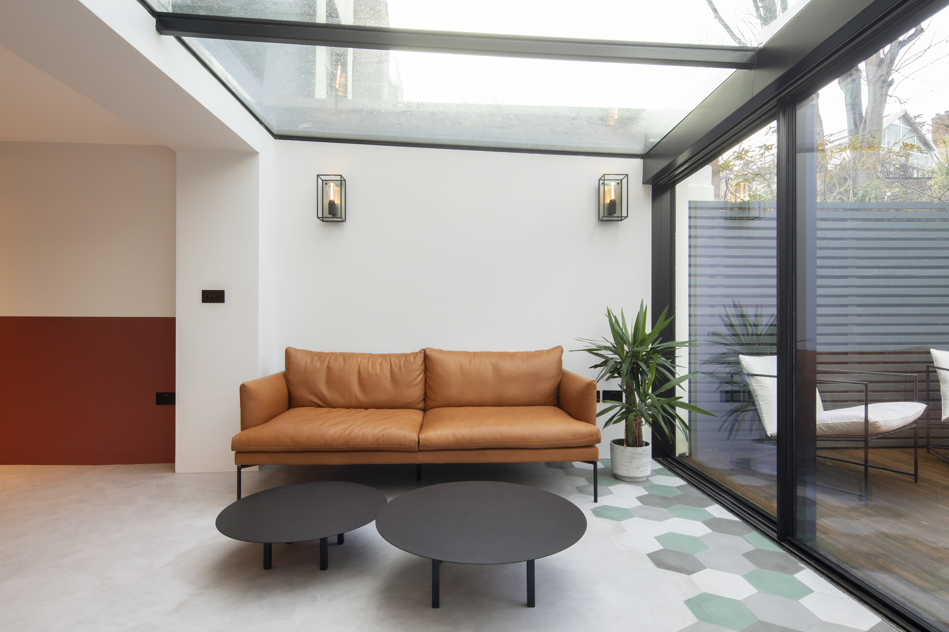 Modern conservatory with a leather sofa and patterned cement tiles