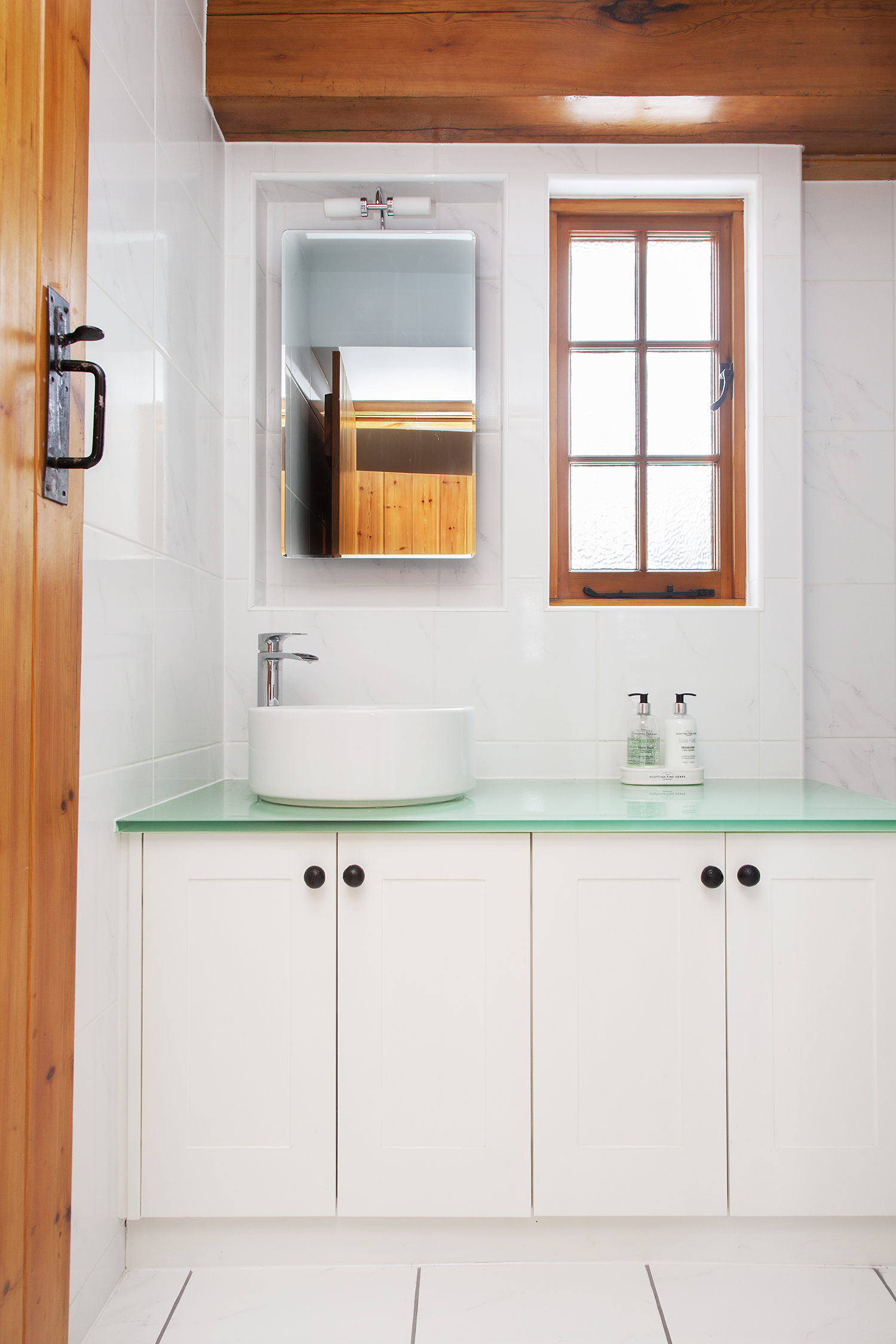 The bijoux bathroom was kept light and white with a splash of colour from the glass surface of the vanity top.