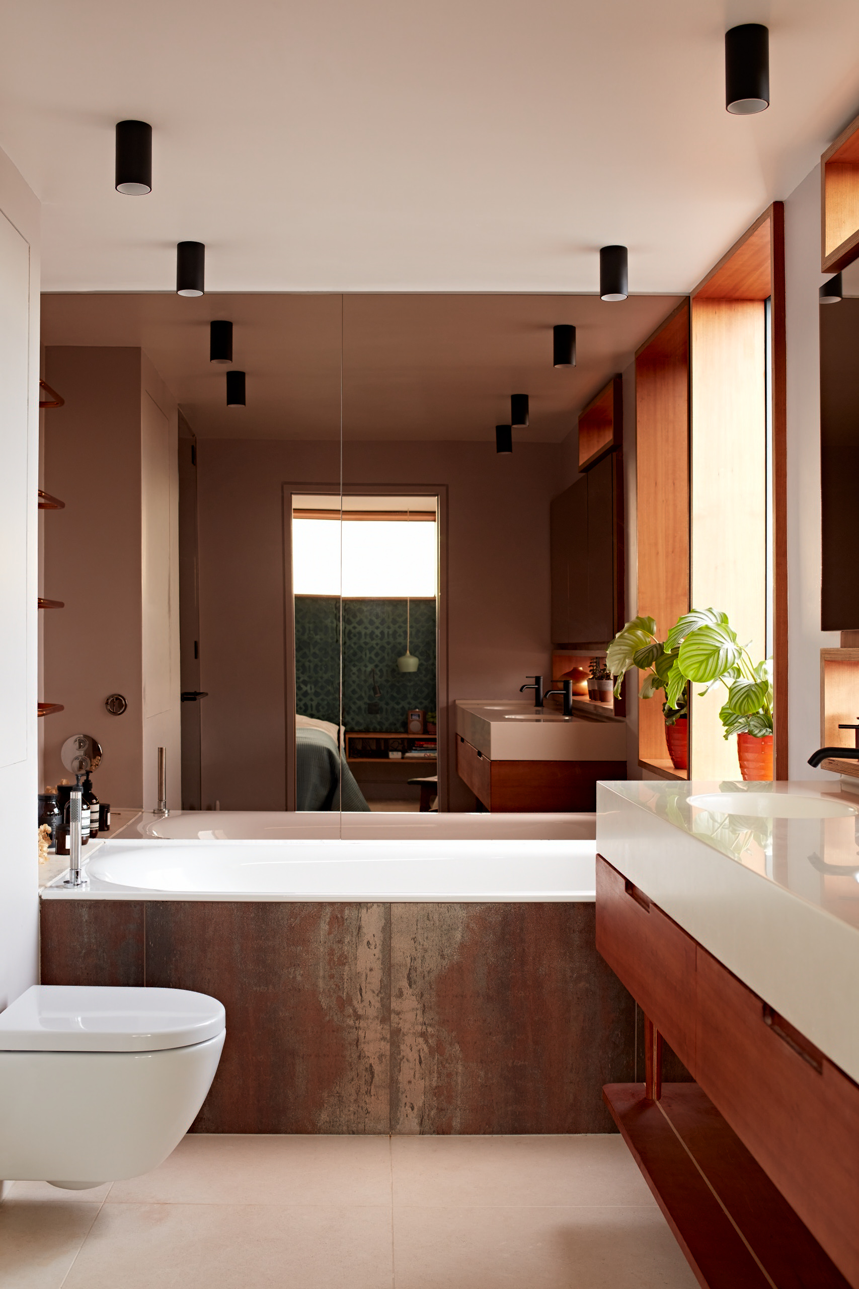 The ensuite features a full length window and bronze mirrored wall alongside a bespoke double vanity unit in cherry and Corian.