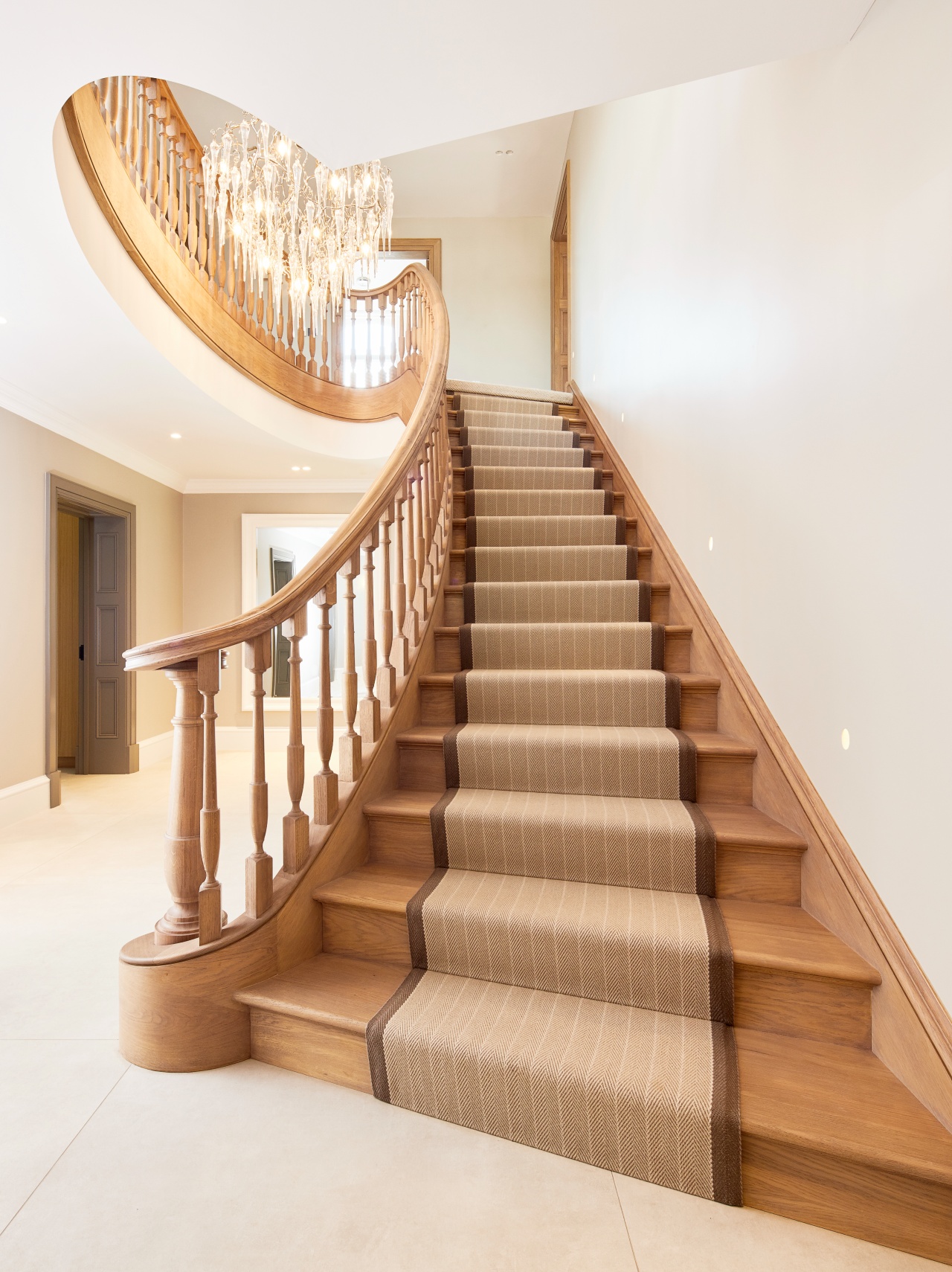 A traditional style elliptical oak staircase with a carpet runner in a house