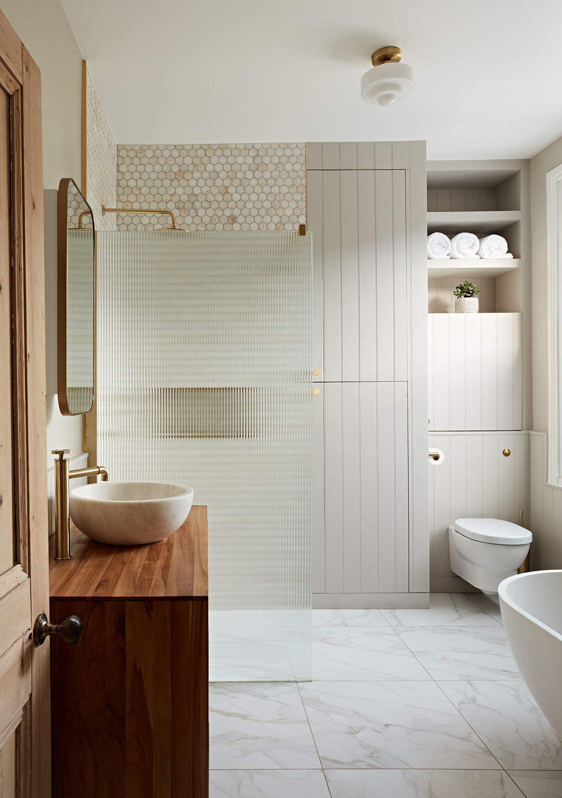 Combining a walnut vanity unit with the marble tiles gave warmth to this contemporary bathroom.