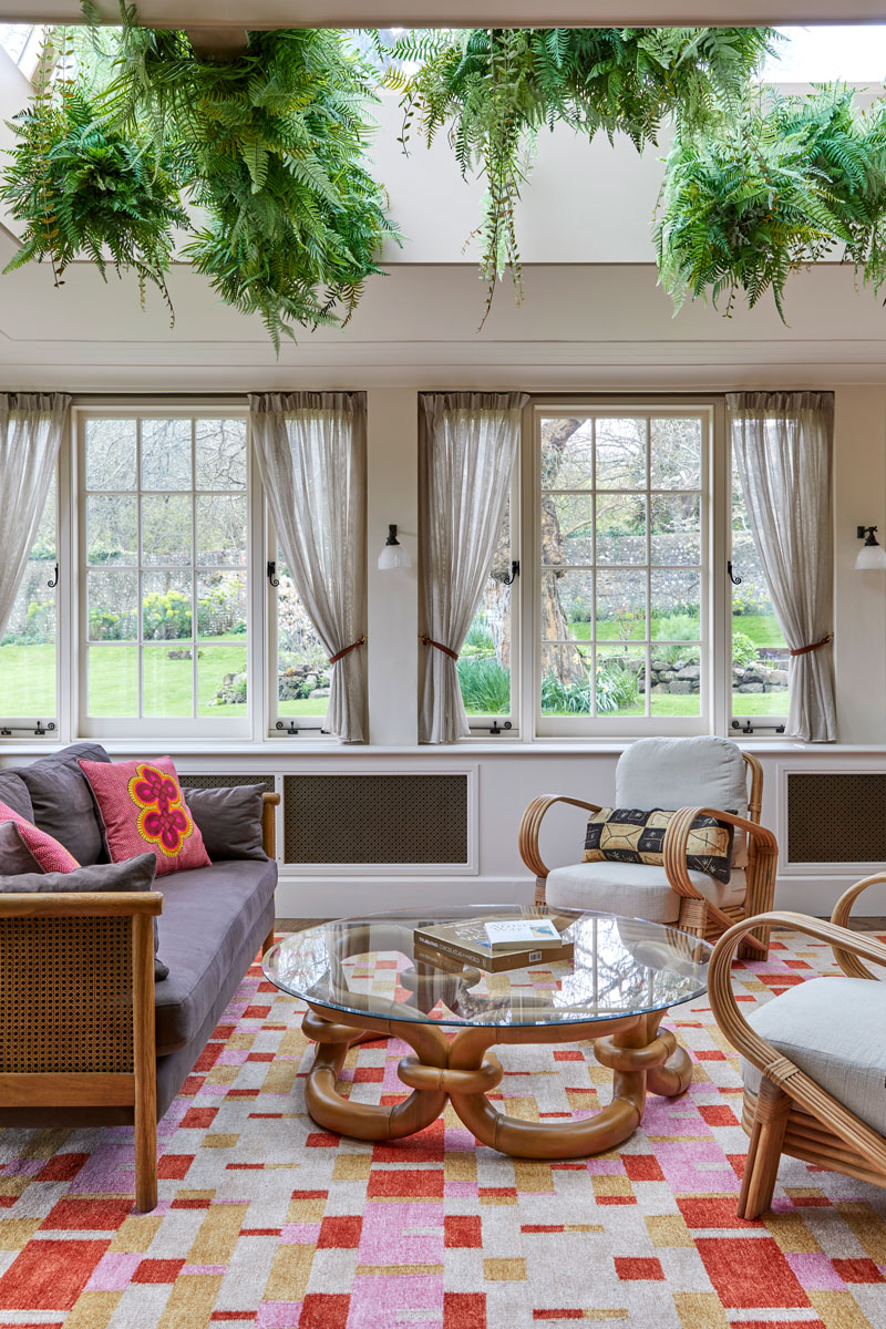 Conservatory with foliage installation, rug and cane furniture