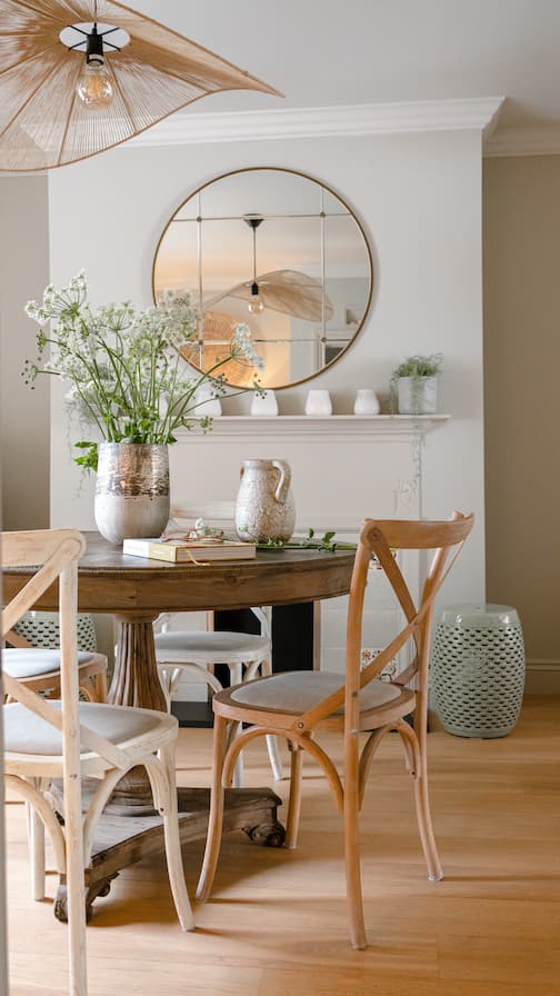 Dining space with large, round mirror and vase filled with fresh flowers