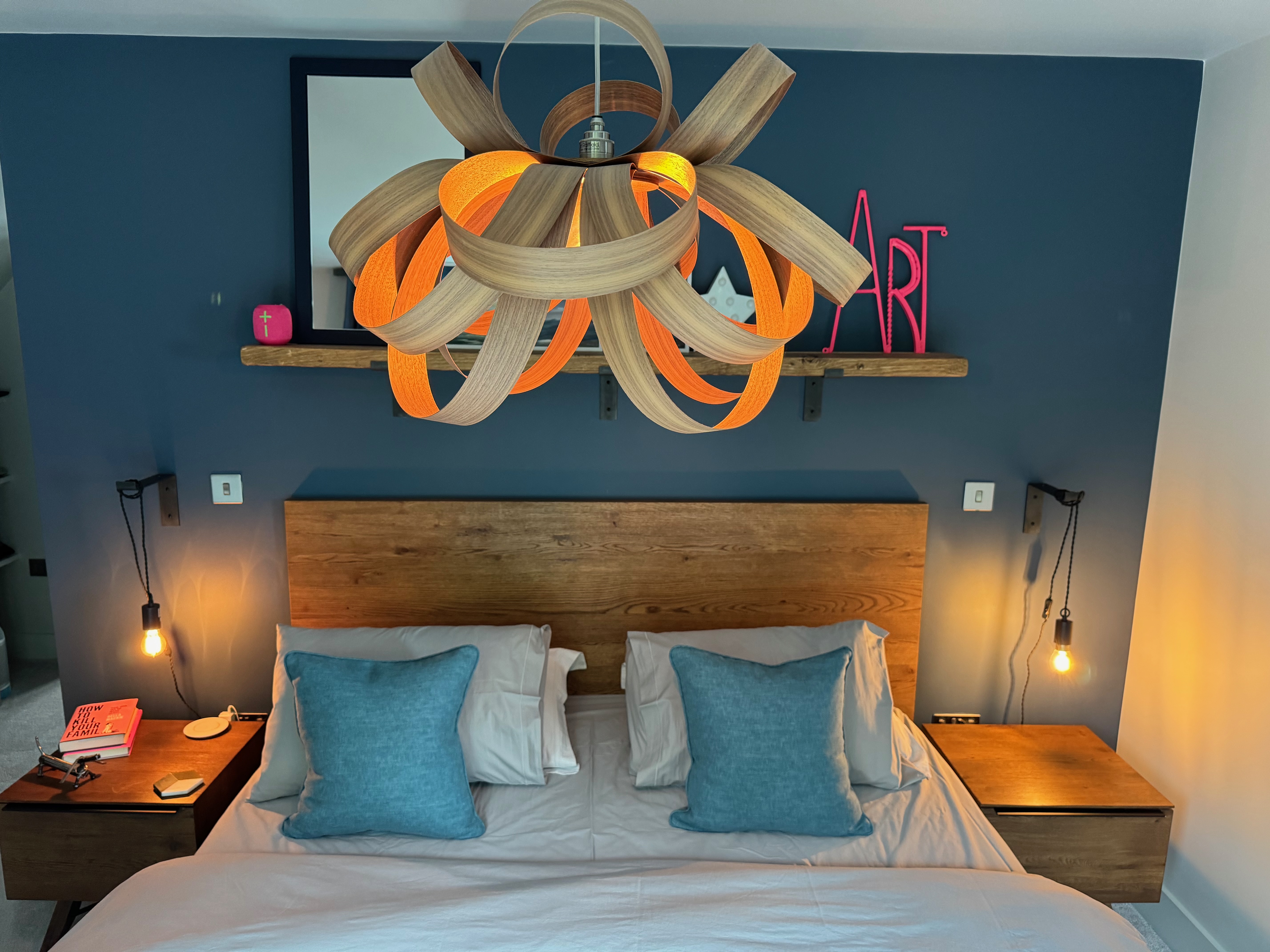 Twisted wooden pendant light above bed in master bedroom