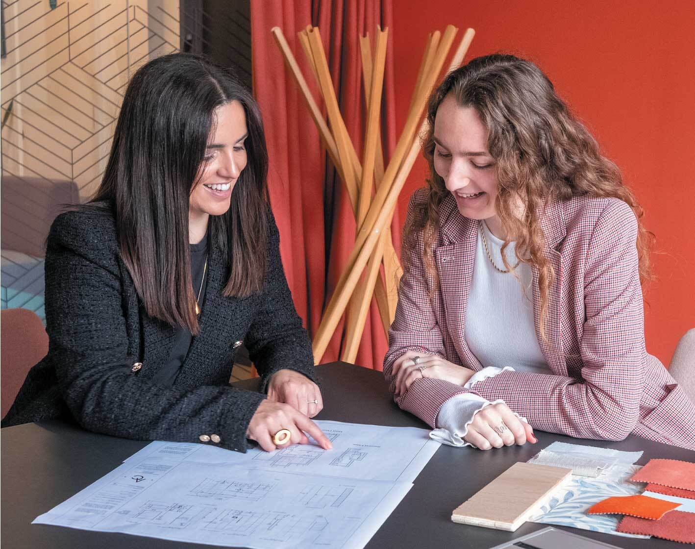 two women at a table looking at plans.