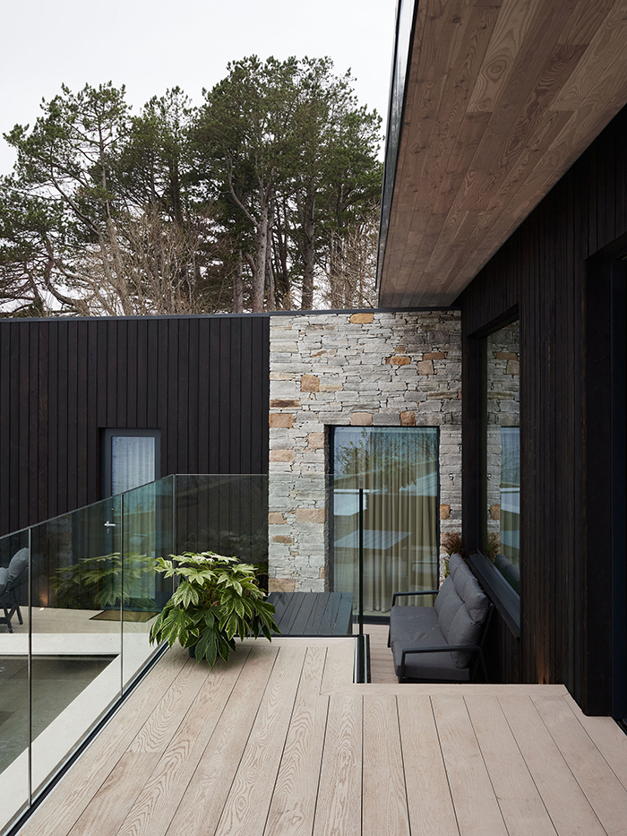 Blackened timber and stone exterior with cantilevered terrace.
