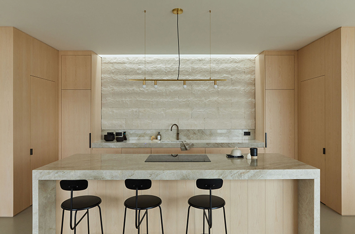 Bespoke ash and marble kitchen with splitface limestone wall.