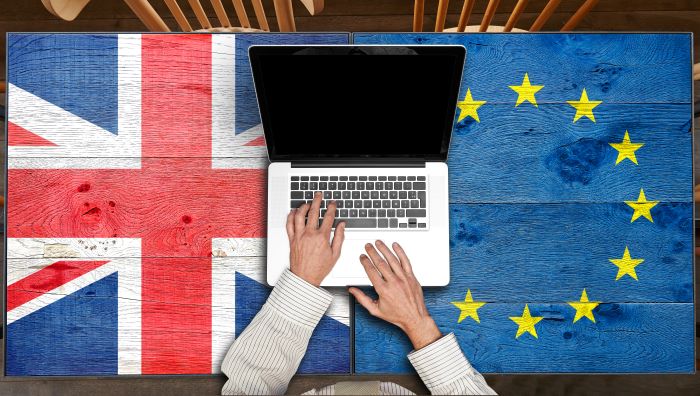 Union Jack and EU flag side by side with a laptop on top.