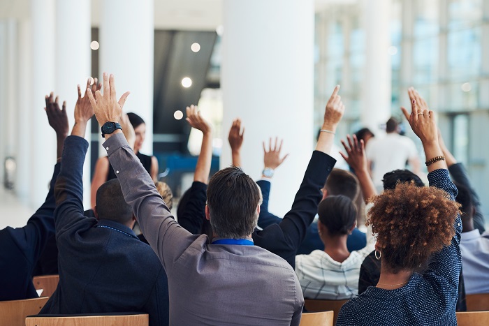 A photo of a group of people with their hands raised in a business meeting