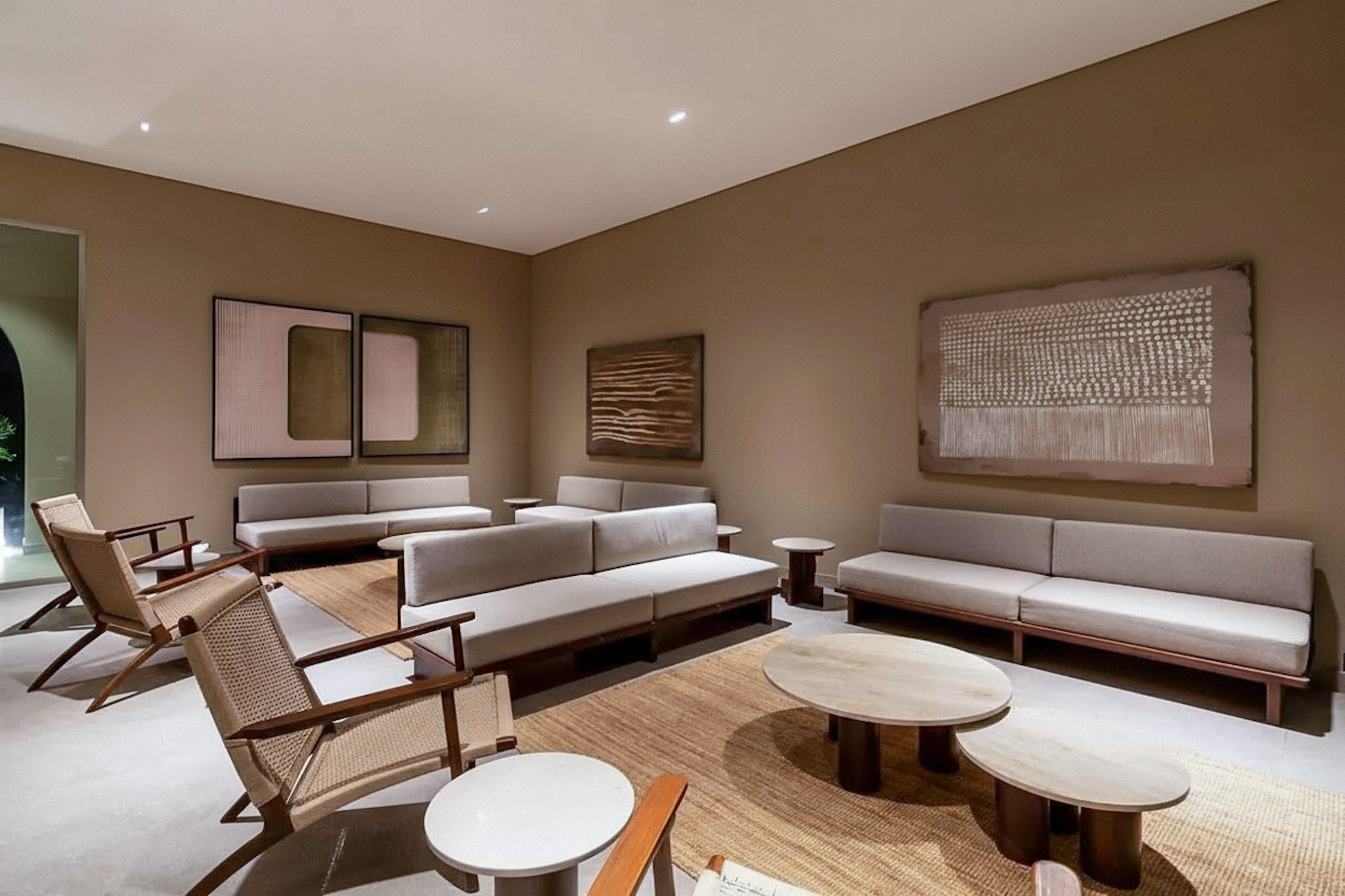 A modern lounge area with beige walls, sofas, artistic wall decor and custom handmade jute rugs