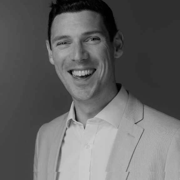 Black and white headshot of Phil Pini smiling into the camera