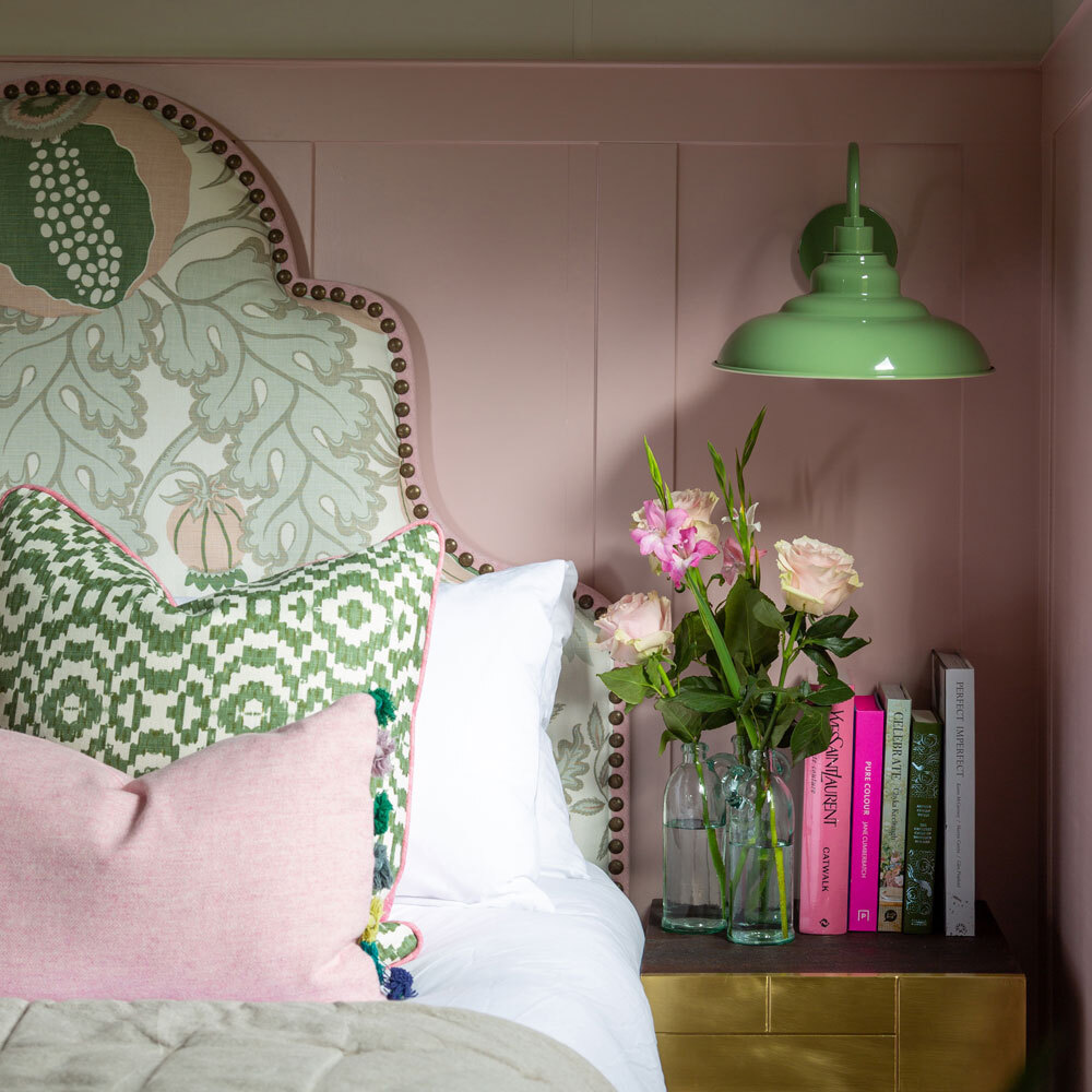 Large headboard on bed with lighting hanging from ceiling