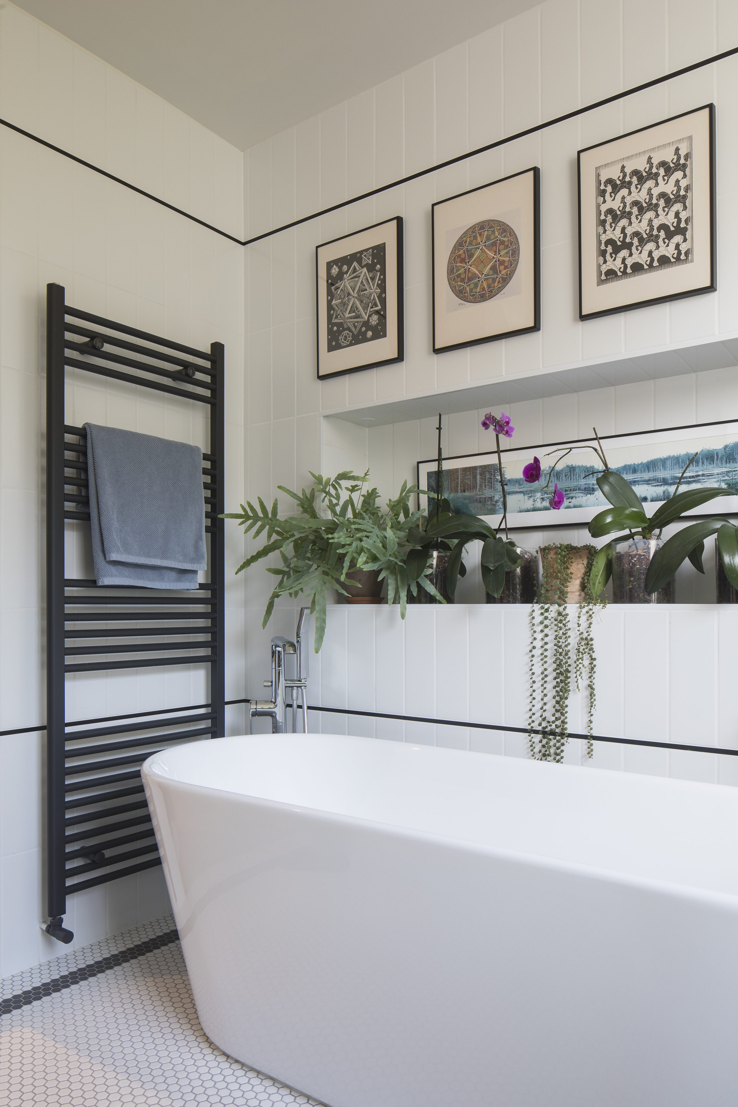 freestanding bathtub with niche full of plants 