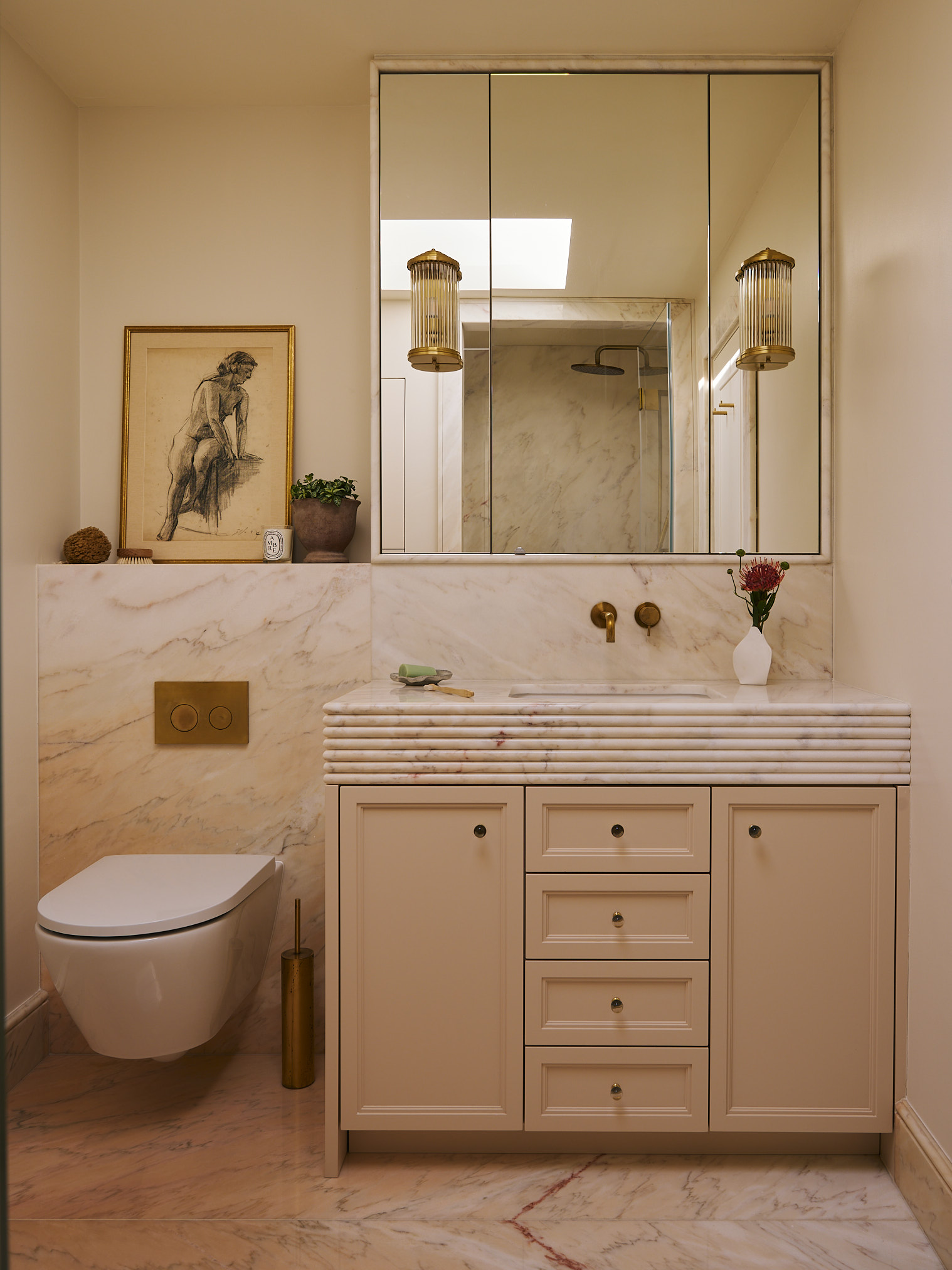 A calm, refined ensuite bathroom where soft stone finishes, tailored joinery, and warm brass details create a balanced and quietly elegant space.