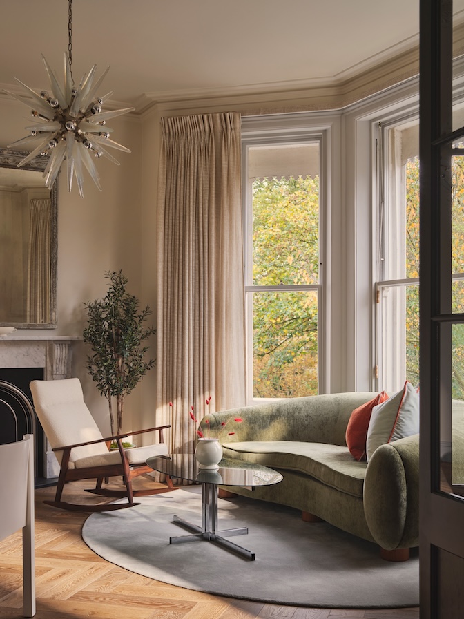 Neutral sitting area with murano glass starburst chandelier, green sofa, vintage rocking chair, and Dedar Sheers  in a Grade II listed apartment