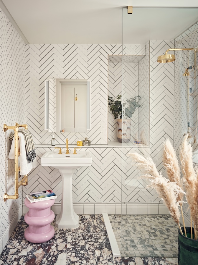 Shower room with herringbone tile, marble flooring, and brass fixtures
