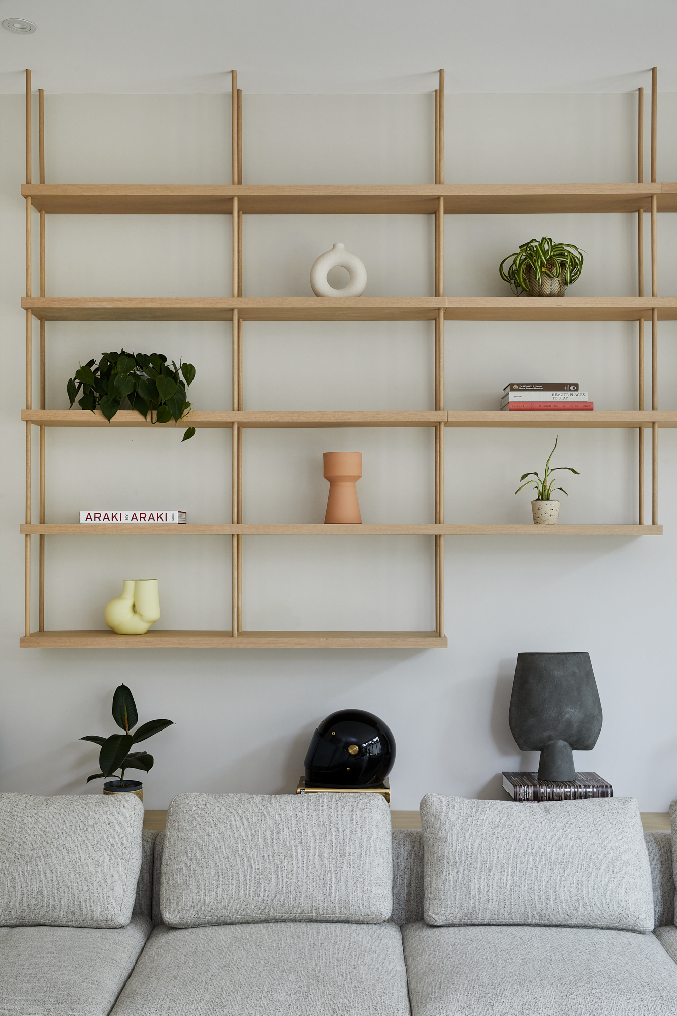 Bespoke wall shelving hung from the ceiling above a sofa by Origins Design