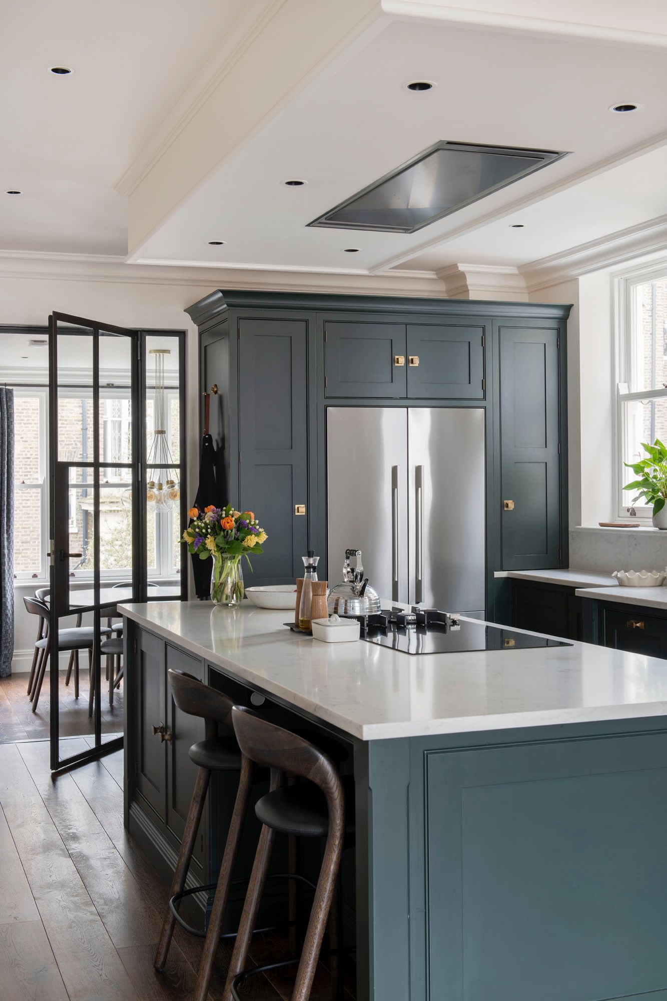 Bespoke dark-green kitchen with marble worktops and black-framed glazed doors in a Notting Hill apartment, designed by Cindy de Vos.