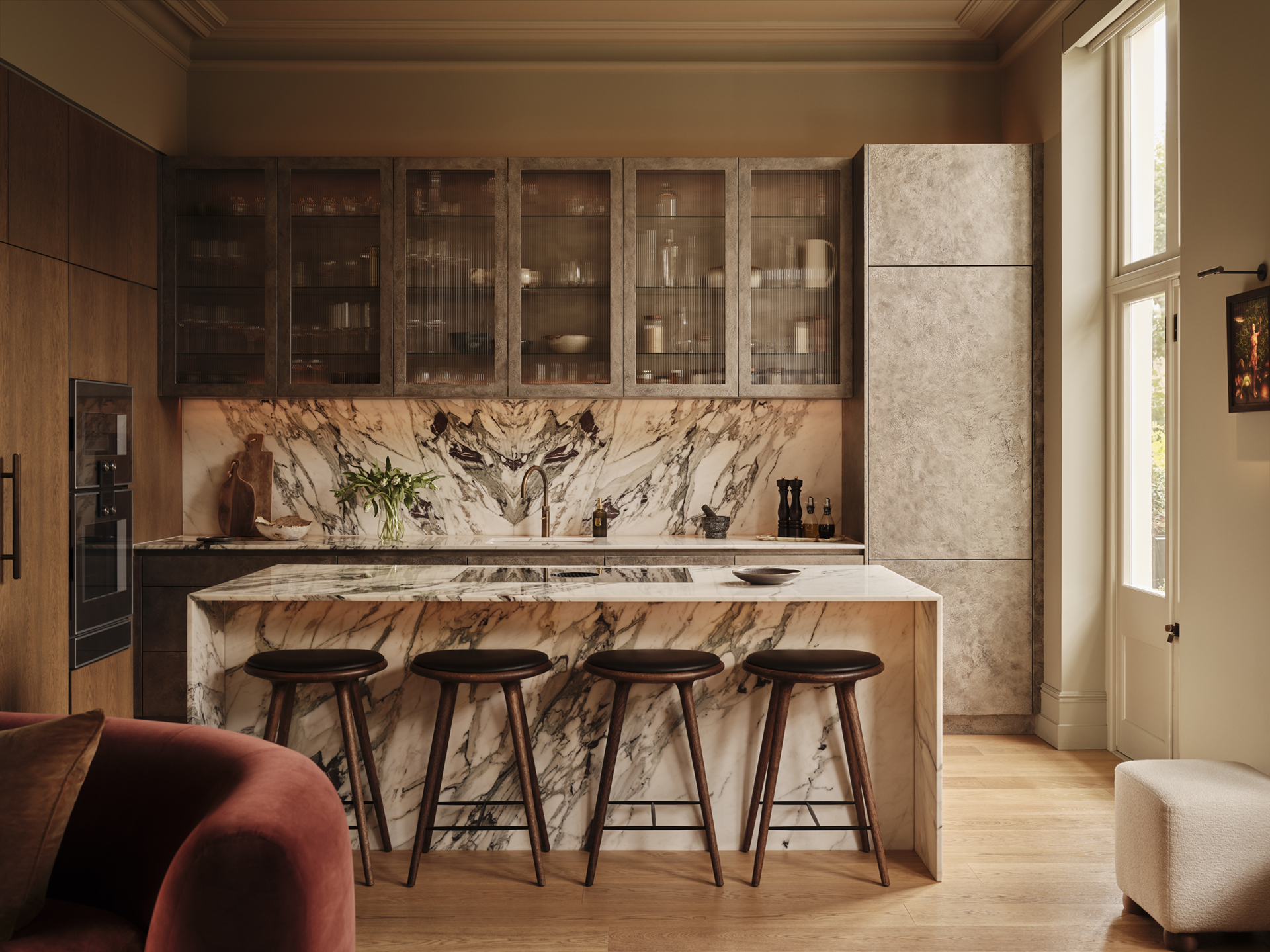 Kitchen with richly veined stone surfaces, glazed wall cabinets and four bar stools arranged along the island, designed by Designed by Woulfe.
