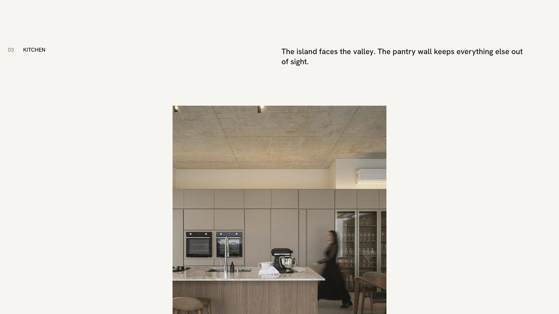 The kitchen on the Quist website: an island facing the valley, with the pantry wall behind