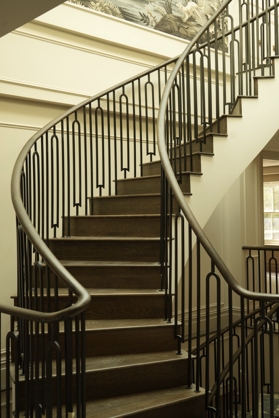 Oak treads and the bronze balustrade, climbing past the windows