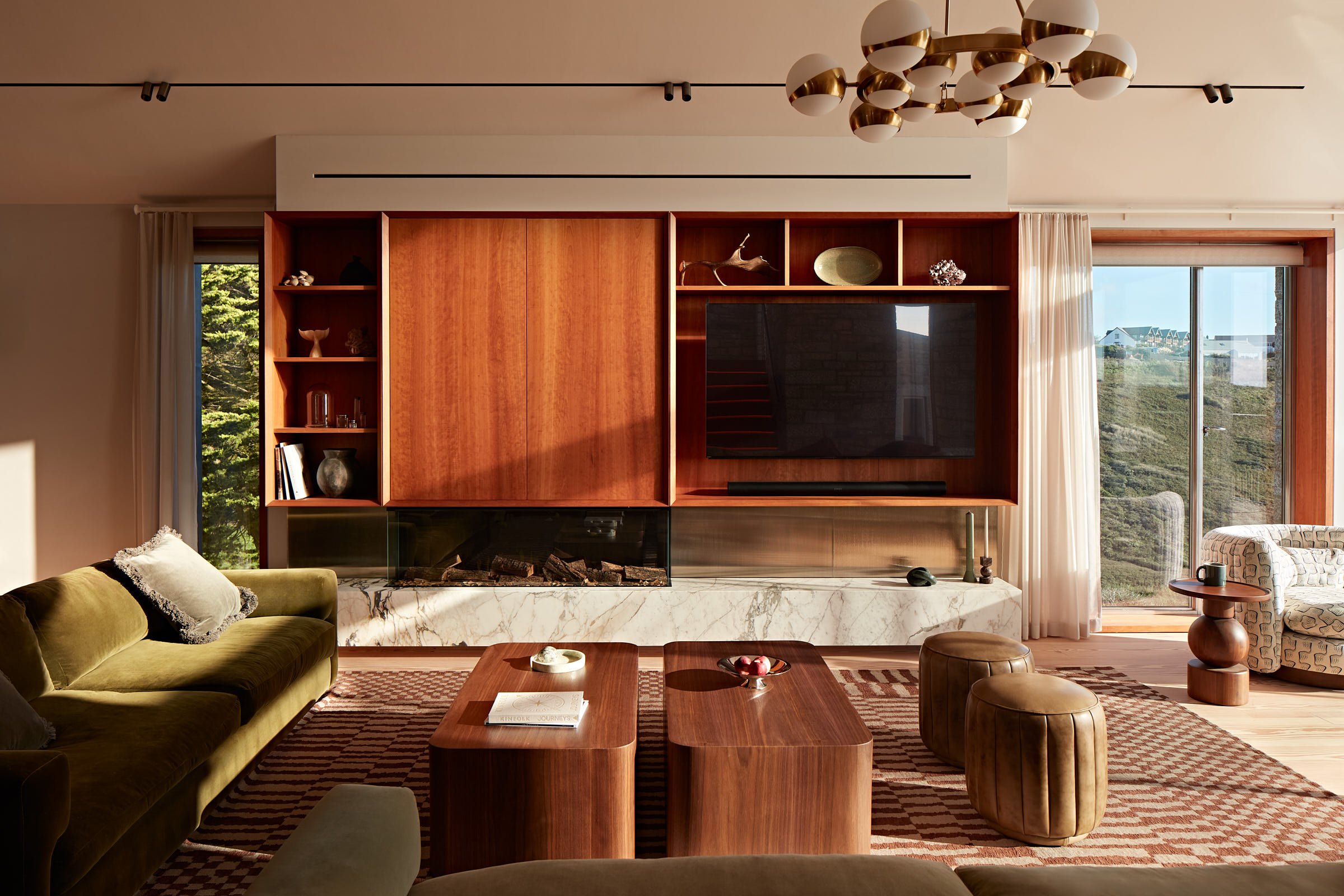 Living room with olive coloured sofa, cherry timber wall shelving and tv unit with statement lighting