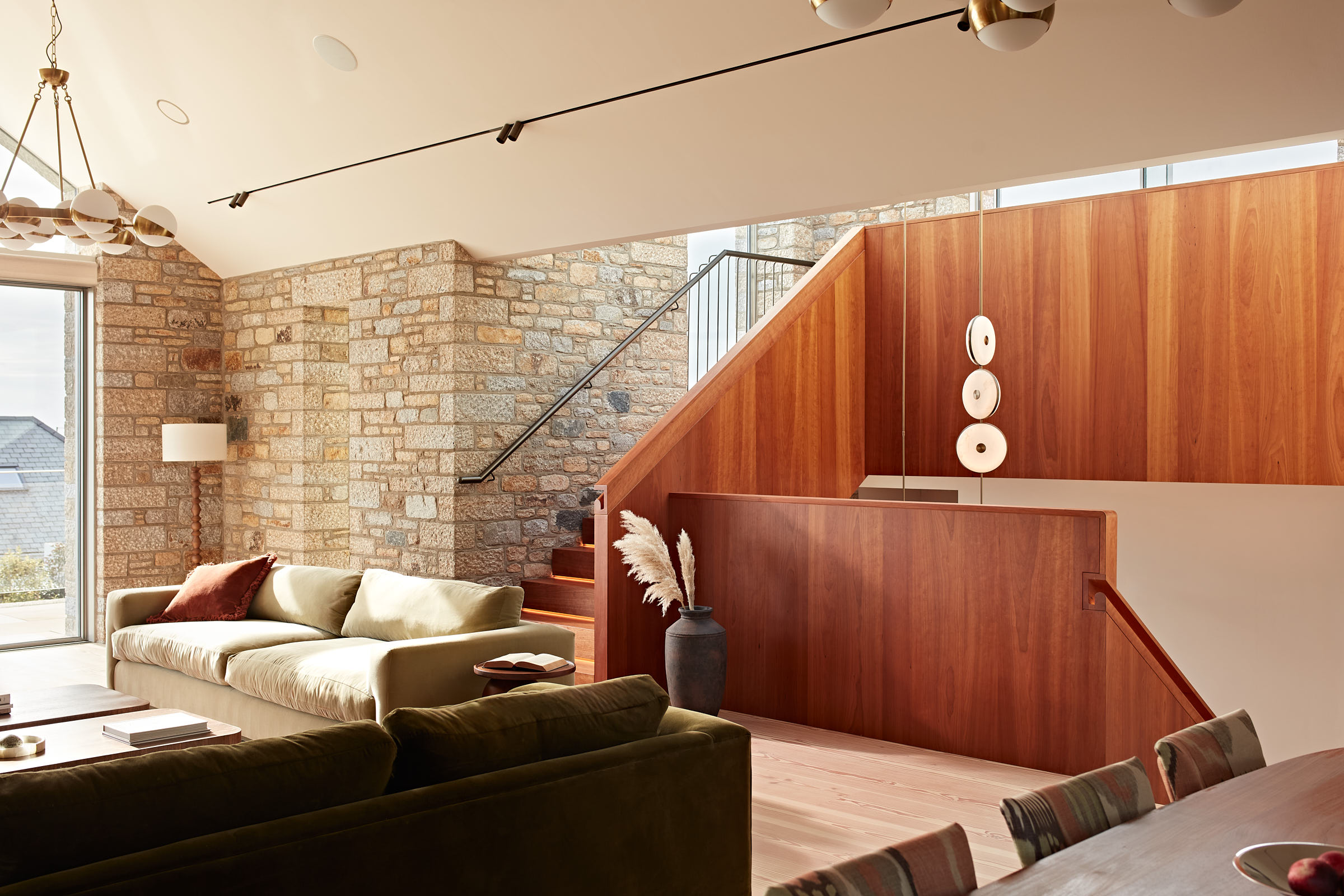 Open plan living room with cherry timber staircase, granite wall and statement pendant light
