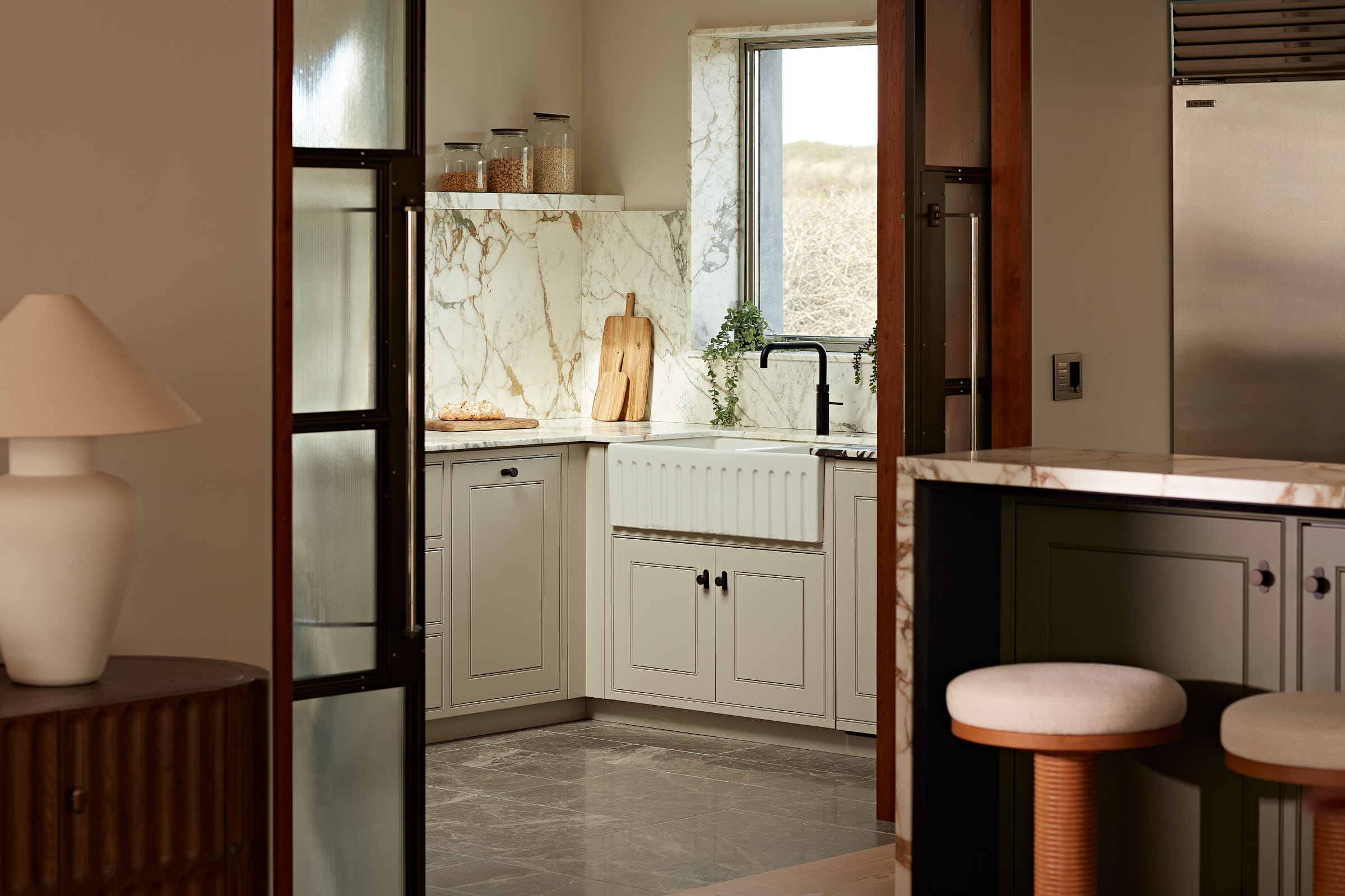 Sliding glazed doors through to modern shaker style kitchen Calacatta Monet marble & fluted sink