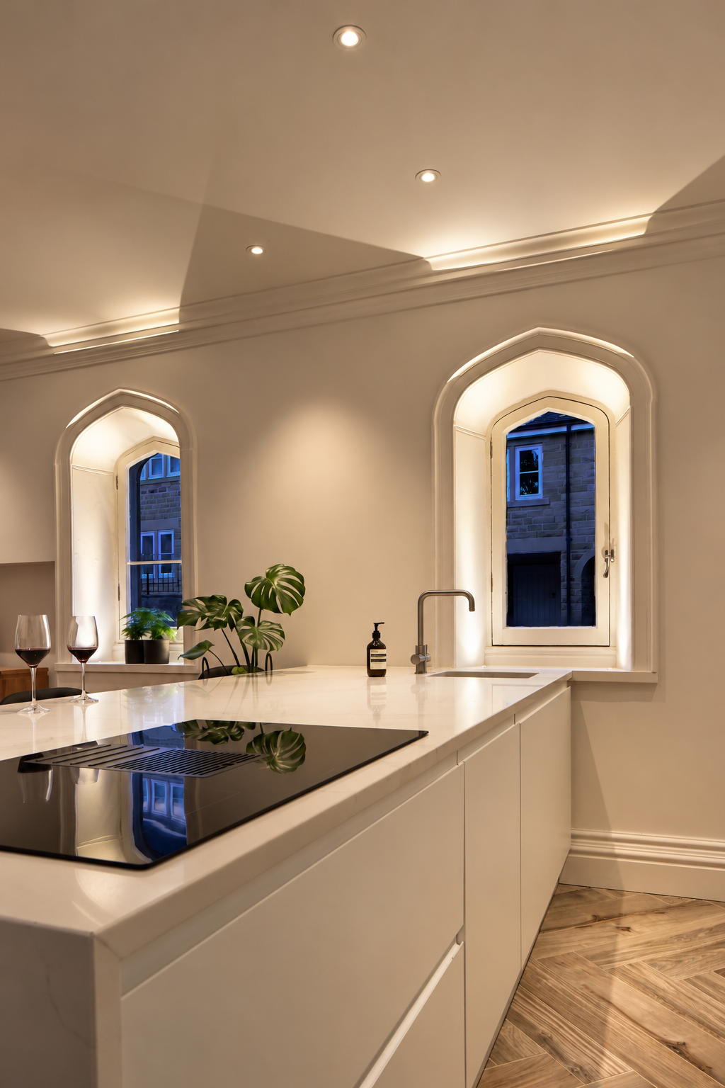 Illuminated arched windows beside the kitchen island and integrated hob at Carter Manor, Wilmslow.