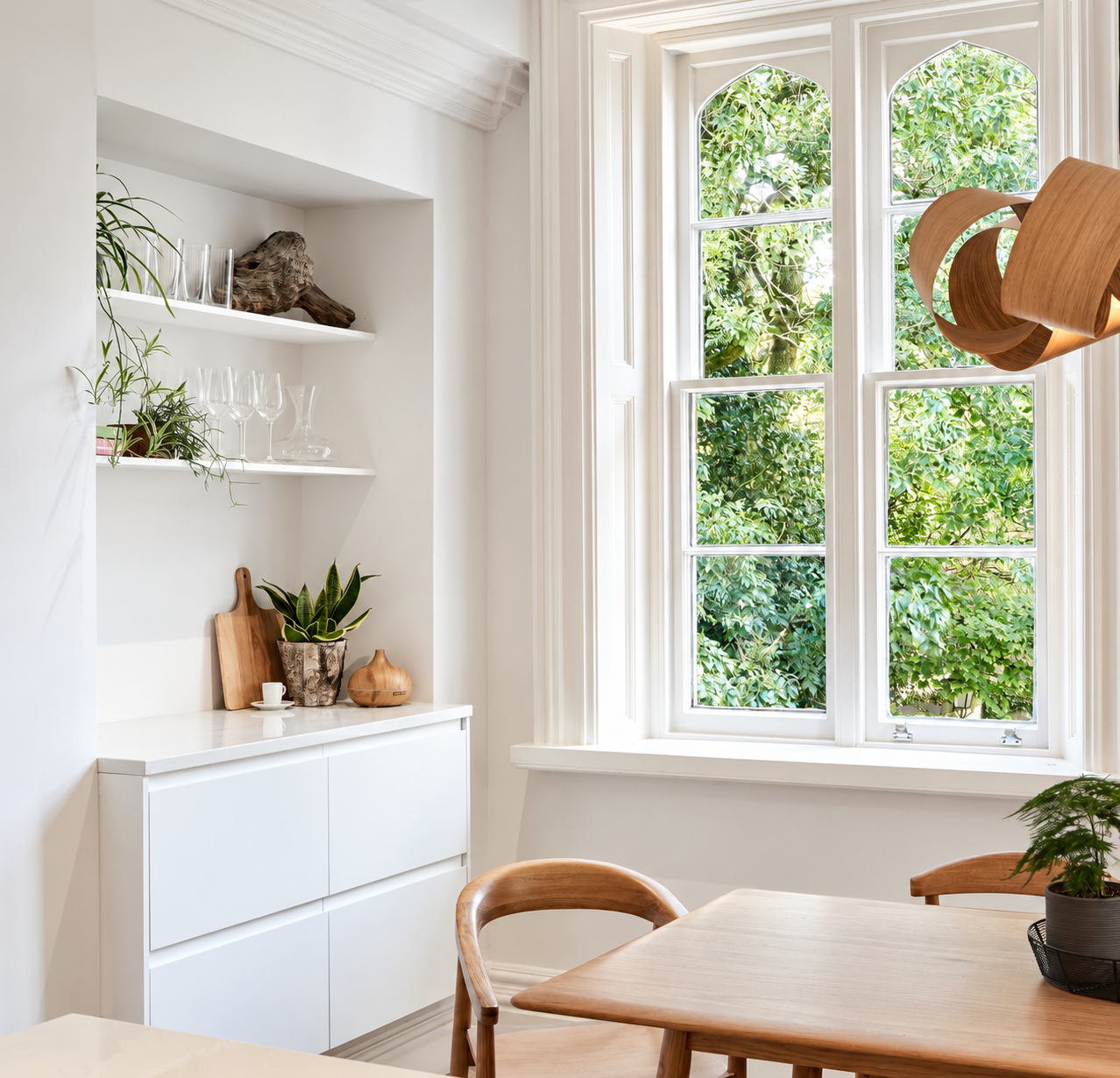 Oak dining furniture and a sculptural wooden pendant beside period windows at Carter Manor, Wilmslow.