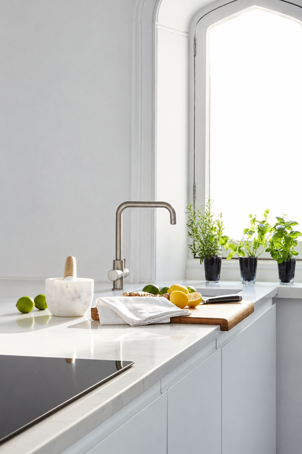 Potted herbs, citrus fruit and a marble mortar beside the island sink at Carter Manor, Wilmslow.