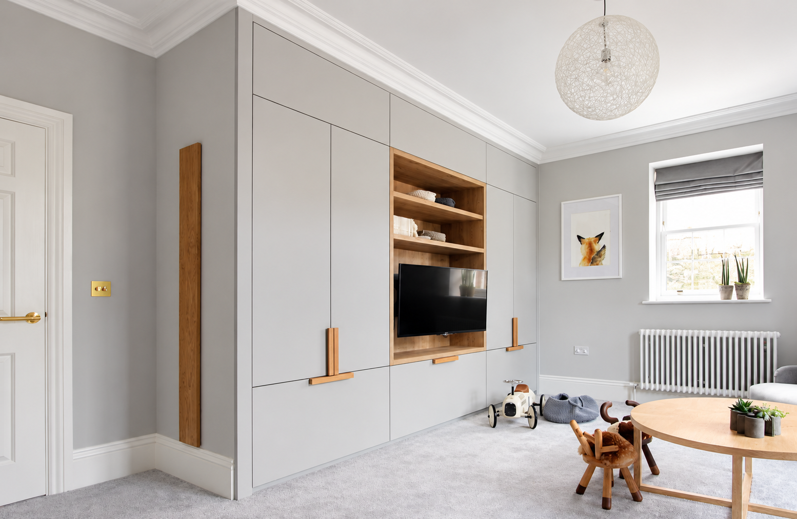 Playroom storage with natural oak handles, open shelving and animal chairs.