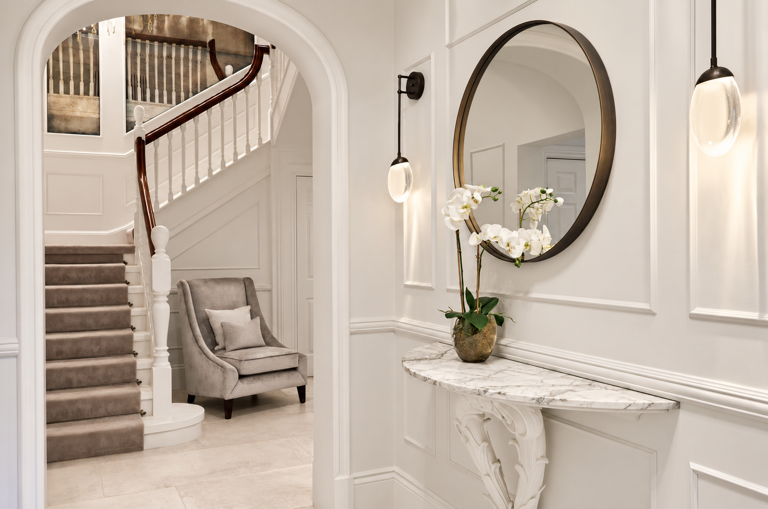 Elegant entrance hall with marble console, orchid and view towards the staircase at Mulberry Lodge, Hale.