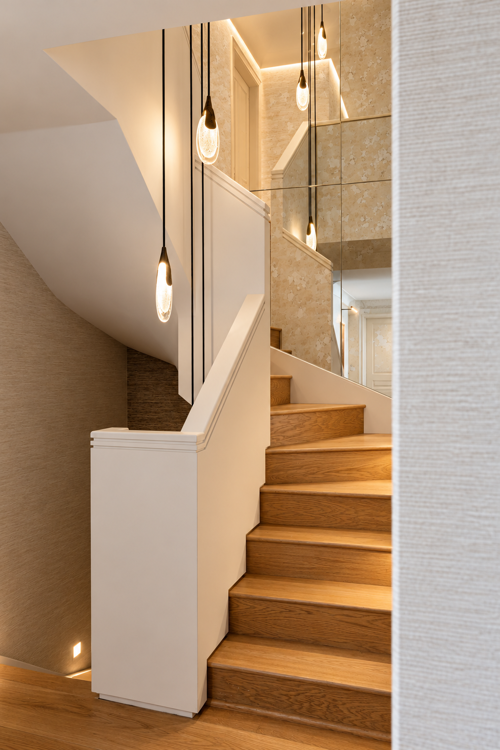 Oak staircase with a plastered balustrade, recessed step lights and a chandelier reflected in antiqued mirror.