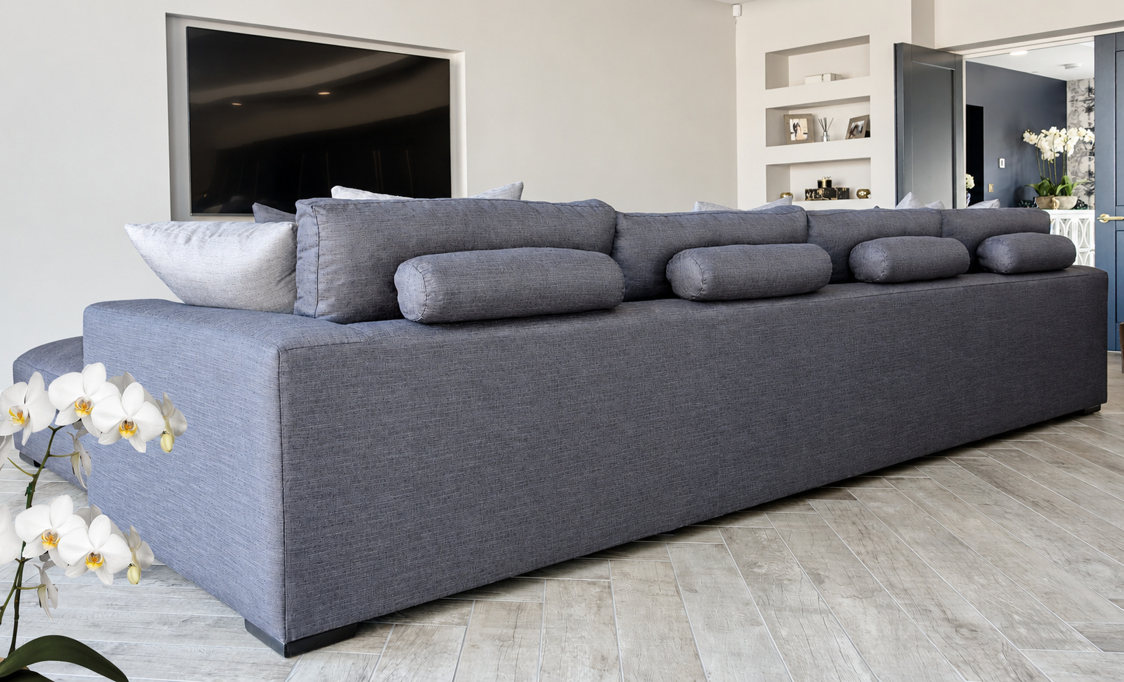 Bespoke blue-grey sofa with bolster cushions overlooking herringbone flooring at The Upton, Prestbury.