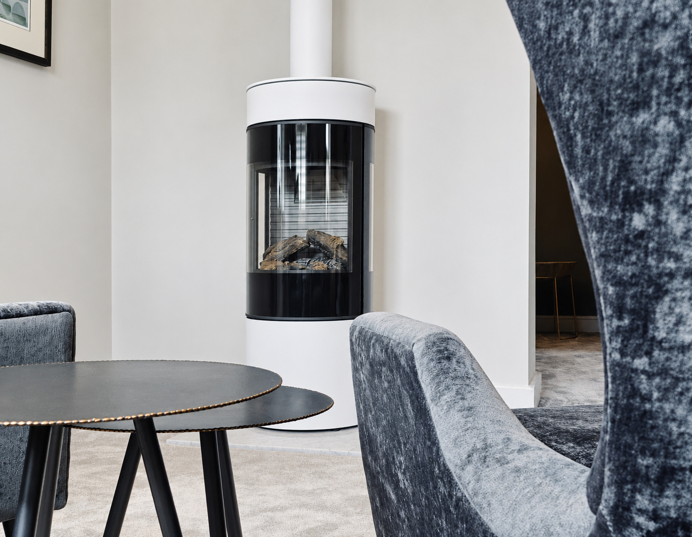 White freestanding stove beside velvet seating and nesting tables at The Upton, Prestbury.