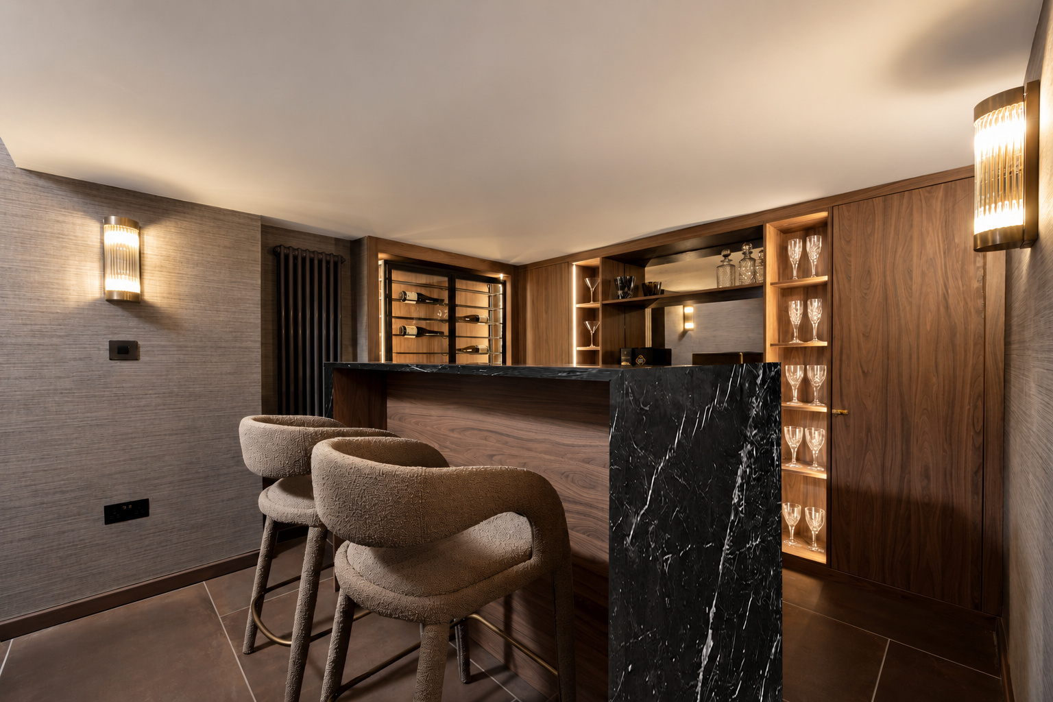 Bespoke timber home bar with a dark veined counter, upholstered stools and lit shelving at The Vault, Alderley Edge.