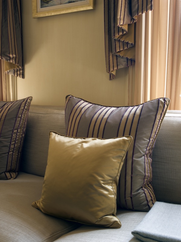 The colour palette is neutral but with accents of rich gold, and aubergine, browns and beiges, which are shown on the ornate cushions.