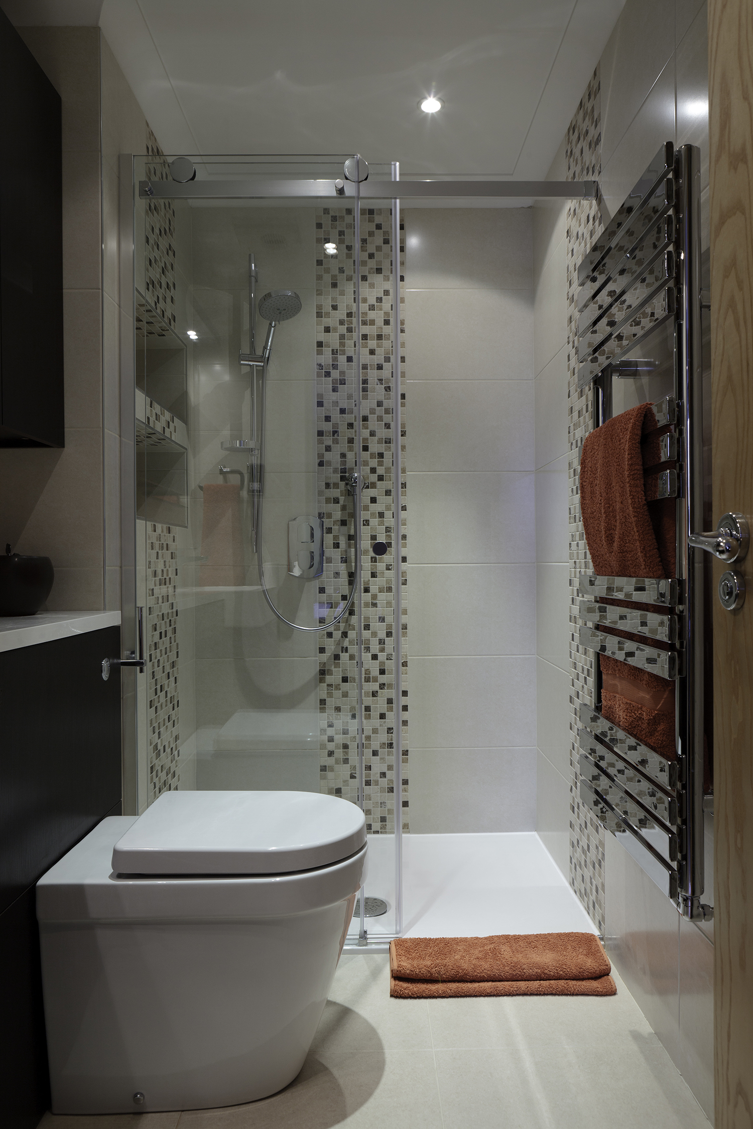 The en suite is clad in a mix of limestone and mosaic. Orange accents are a feature of all the rooms in the flat.