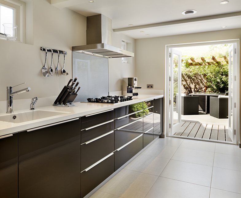 High gloss chocolate units and a sleek white Corian top make this kitchen feel spacious and glamorous.