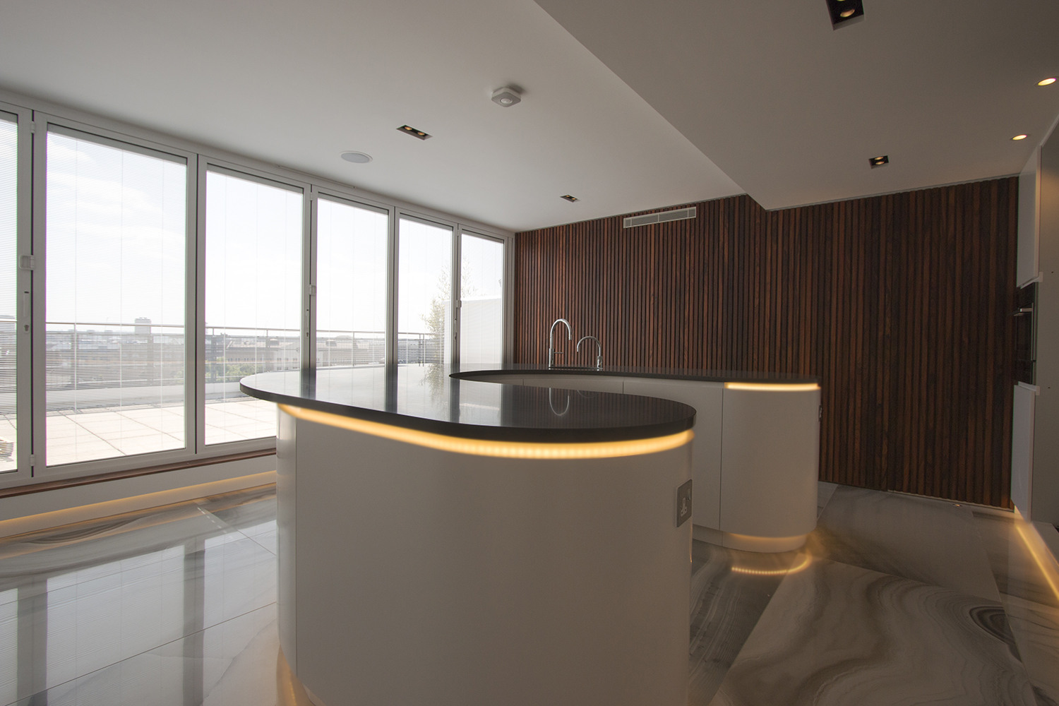 The horseshoe shaped kitchen encourages people to circulate. The rosewood wall panels conceal a door to the study.