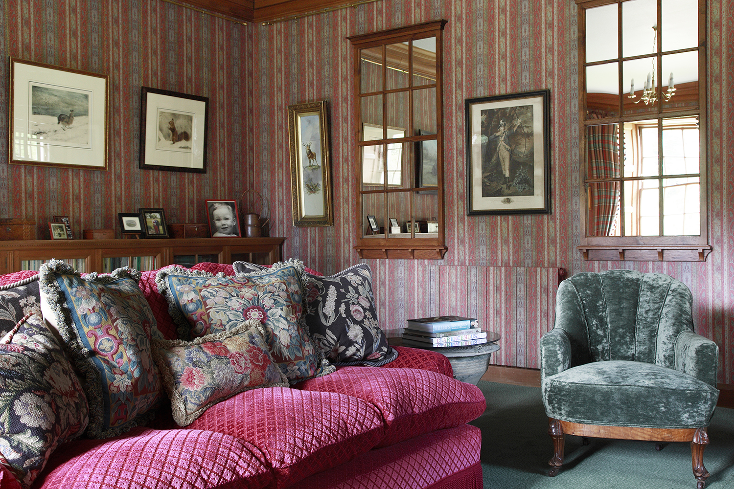A brightly coloured paisley striped paper sets the tone for sofa and chairs in pinks, red and greens in this cosy room.  