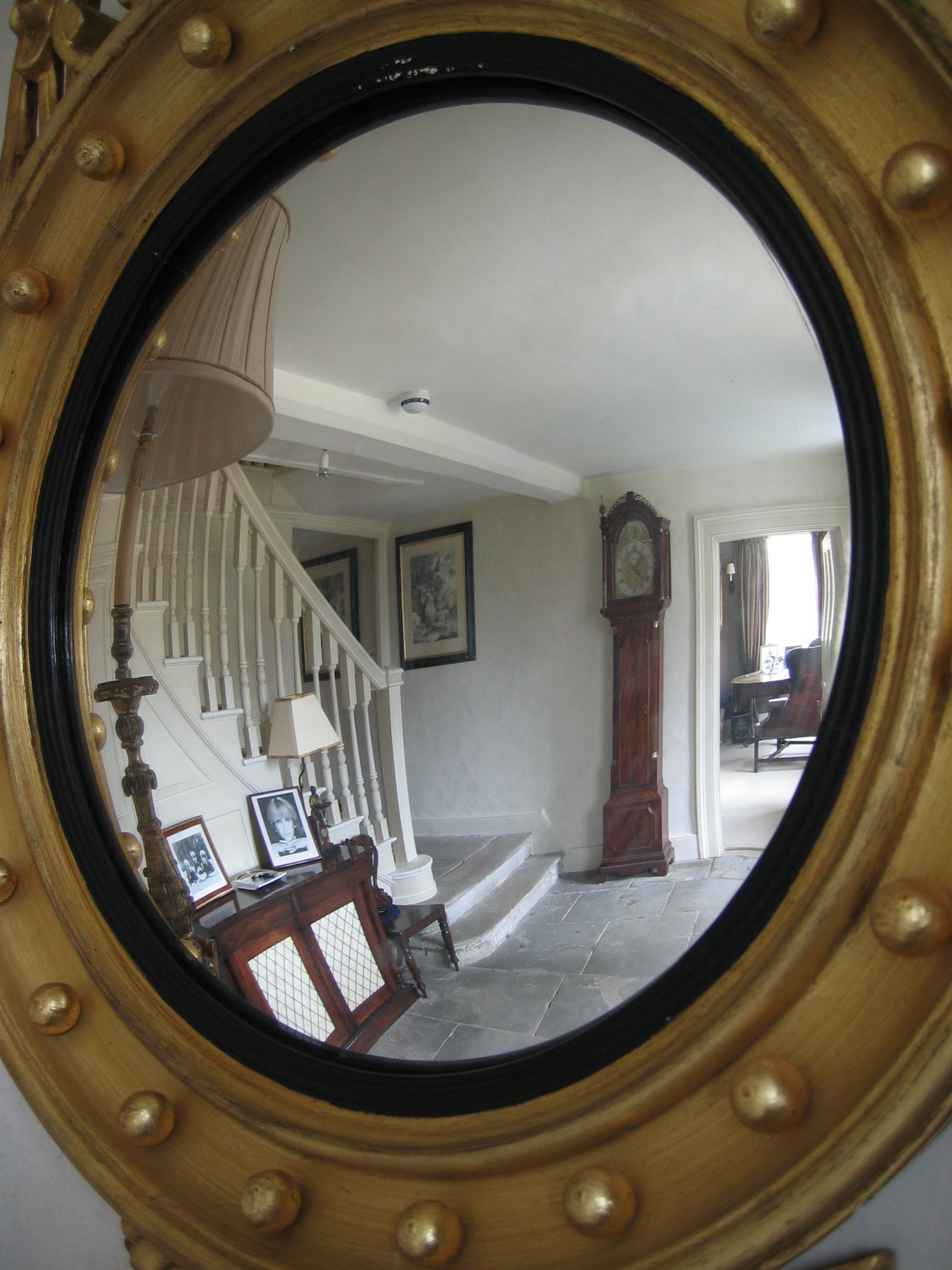 Antique flagstones and a stone washed specialist paint finish on the walls are reflected in the convex hall mirror.