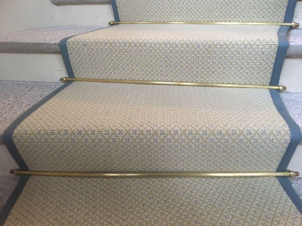 Close up of bordered carpet with fitted brass stair rods