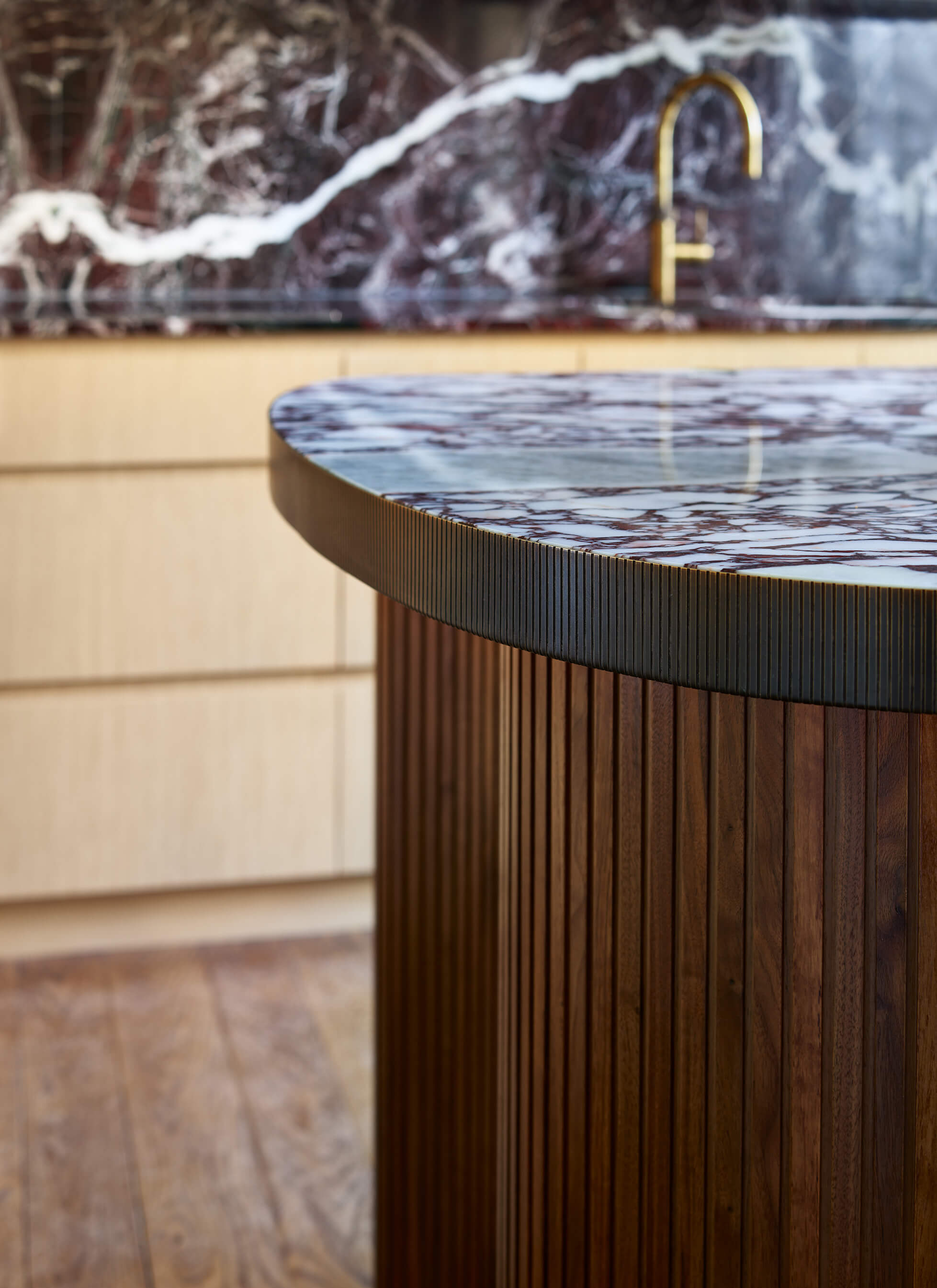 The edge of the marble worktop on the island is wrapped in a machined bronze band
